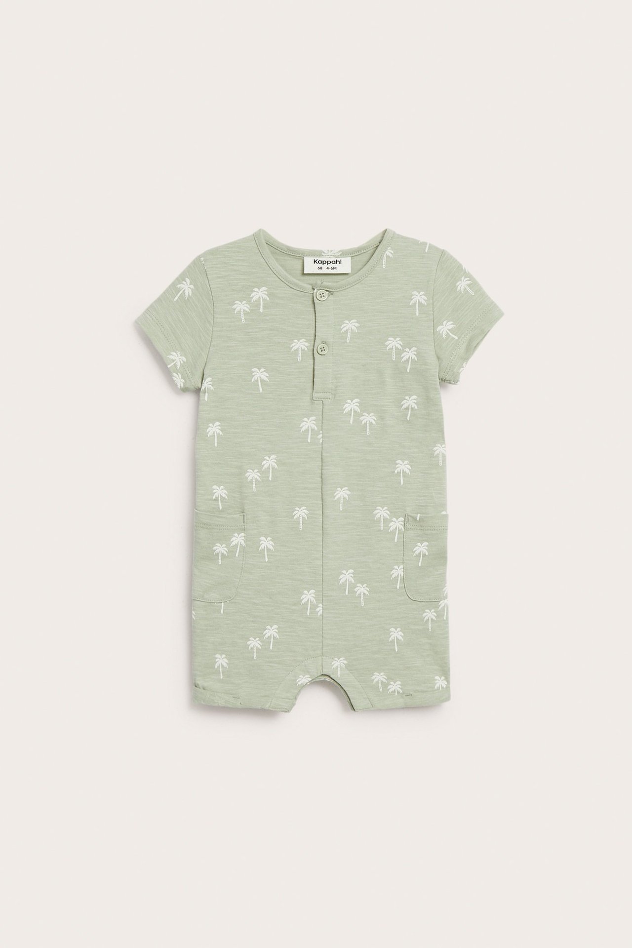 Widok z przodu: Jasnozielony, krótki bawełniany pajacyk niemowlęcy z białym wzorem palm, guzikami i bocznymi kieszeniami.