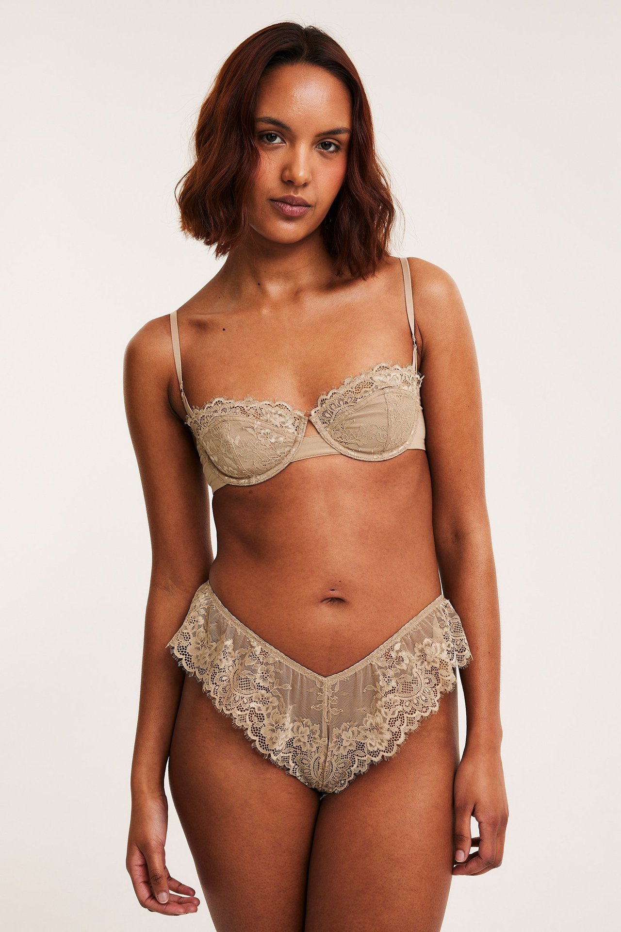 Frontbilde av en kvinne i beige blonde cheeky truse med volanger og matchende blonde-BH.