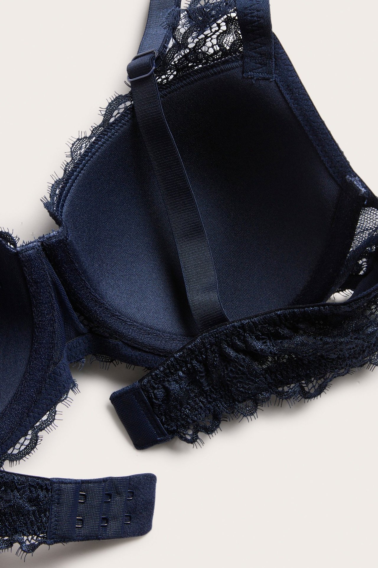 Lähikuva tummansinisistä pitsiliiveistä, joissa on muotoillut kupit ja hakaskiinnitys.