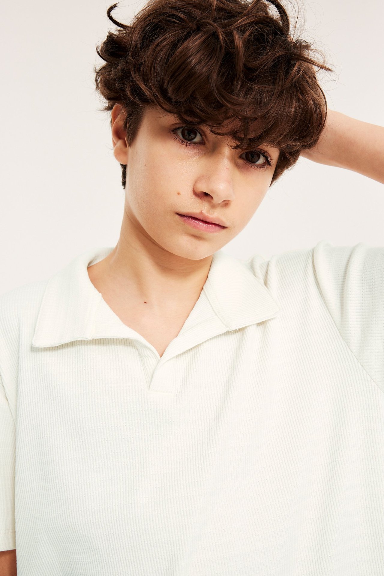 Lähikuva, edestä, lapsesta yllään luonnonvalkoinen, strukturoitu lyhythihainen pikeepaita kauluksella.