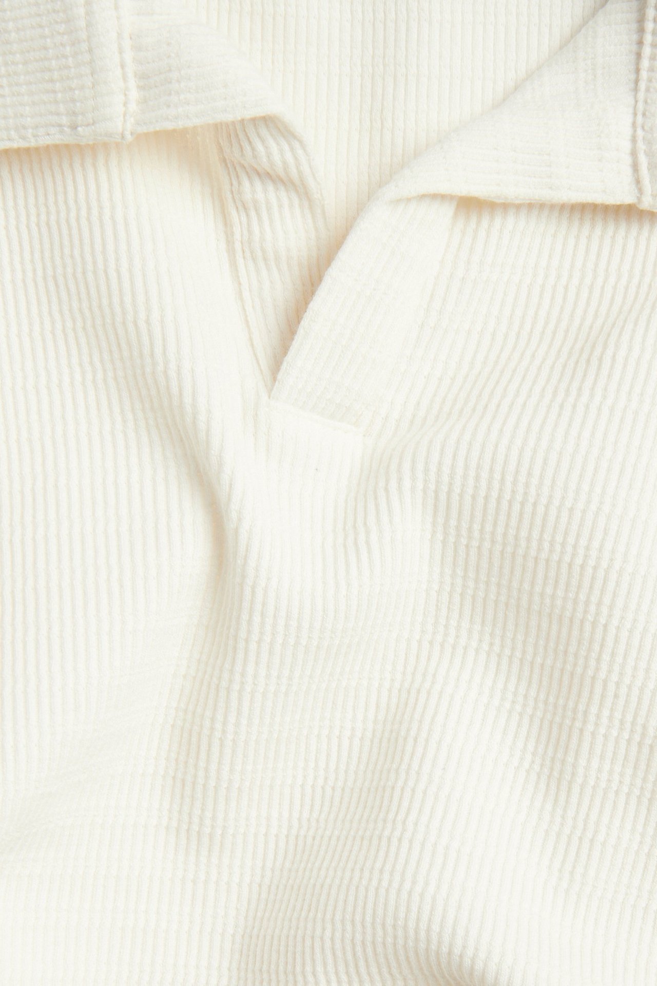 Zbliżenie na ecru, krótką koszulkę polo z fakturowanej tkaniny, z dekoltem V.