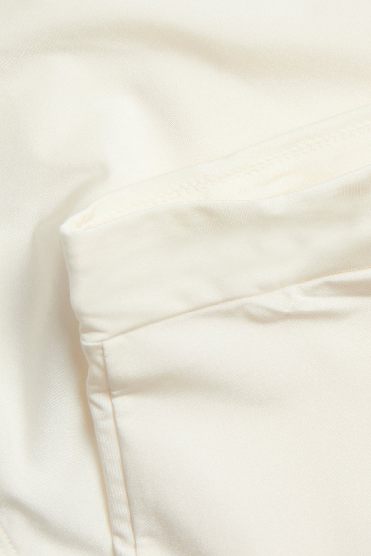 Lähikuva luonnonvalkoisesta korkeavyötäröisestä muokkaavasta alushoususta, jossa on hienoa kiiltoa.