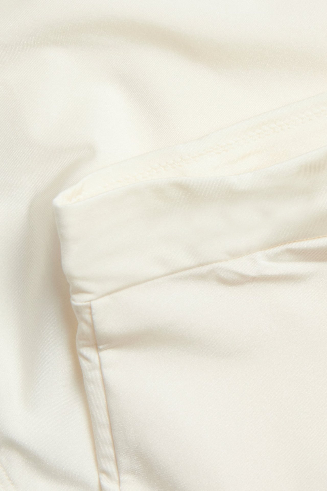 Lähikuva luonnonvalkoisesta korkeavyötäröisestä muokkaavasta alushoususta, jossa on hienoa kiiltoa.