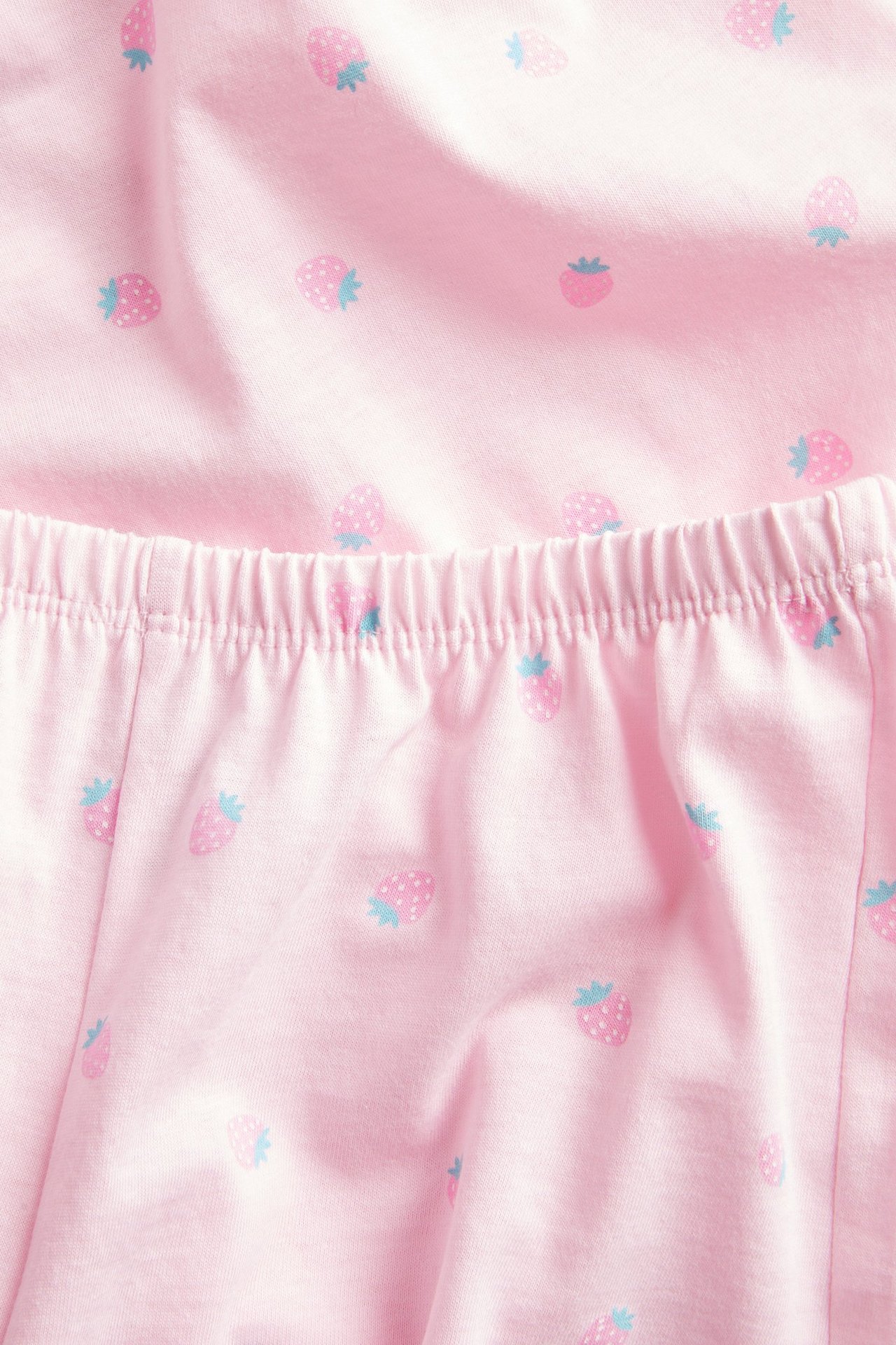 Zbliżenie różowej, bawełnianej piżamy w truskawki z elastycznym pasem.