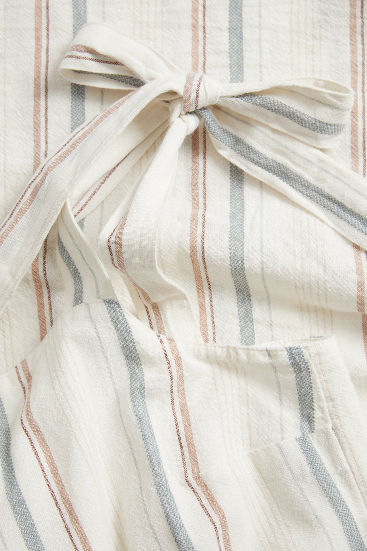 Zbliżenie na sukienkę z off-white bawełny w paski, czerwonobrązowe i niebieskoszare pasy, wiązane ramiączko.
