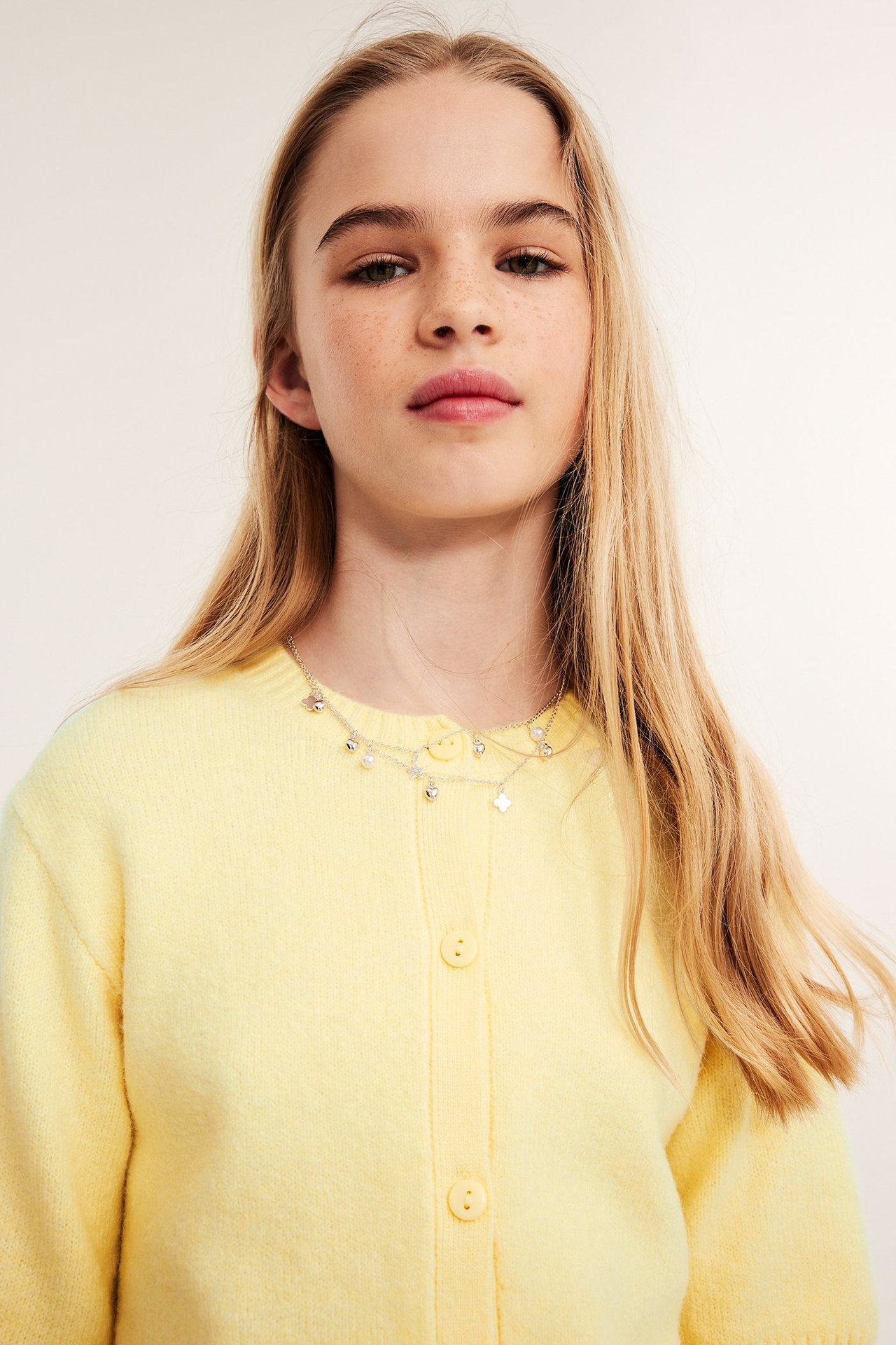 Młoda kobieta z długimi blond włosami w jasnoniebieskim short-sleeve kardiganie, front.