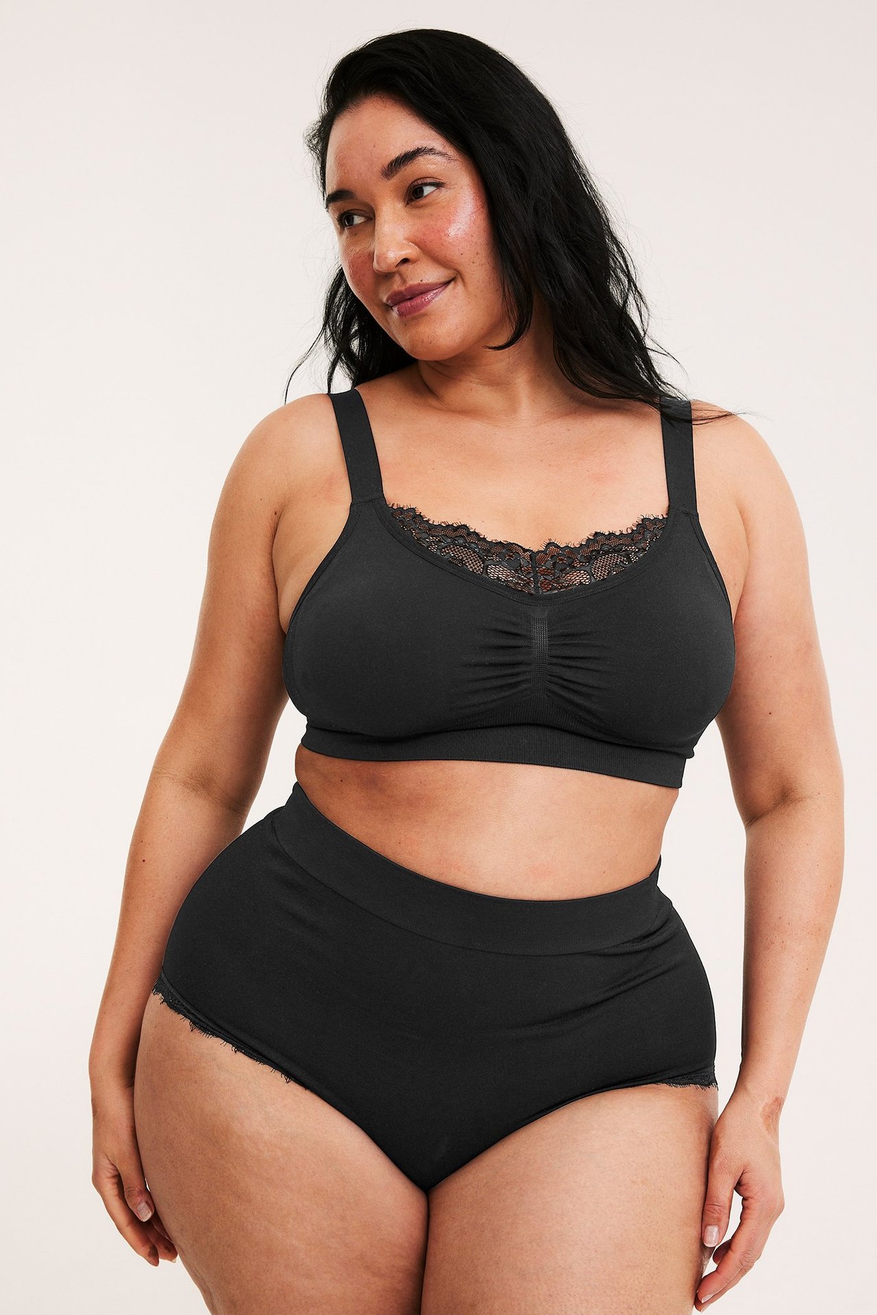 Widok z przodu kobiety w czarnych bezszwowych figach typu hipster z koronką i pasującym biustonoszem.