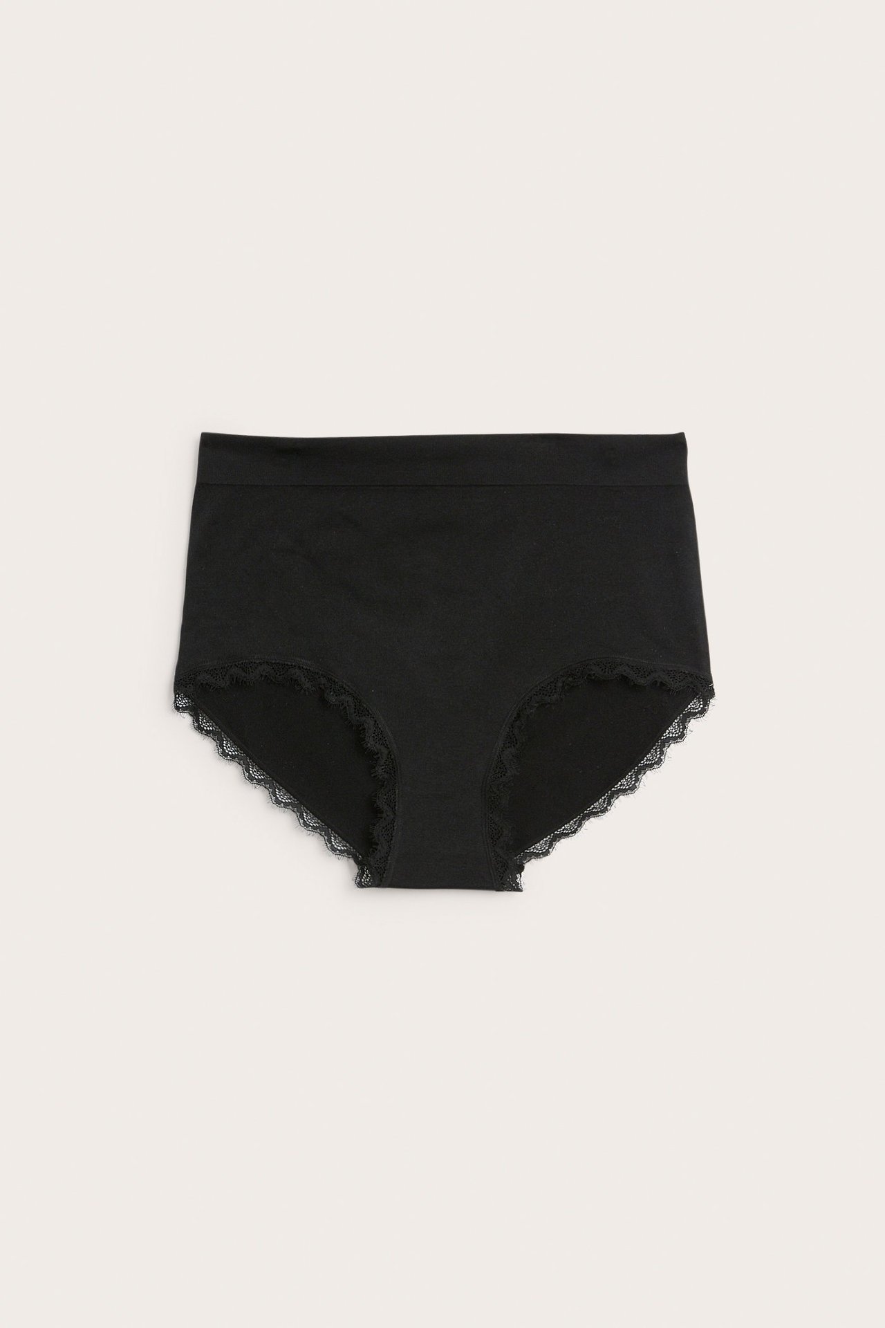 Edestä mustat yksiväriset hipsterit, joissa on hienot pitsireunat jalkojen aukoissa.
