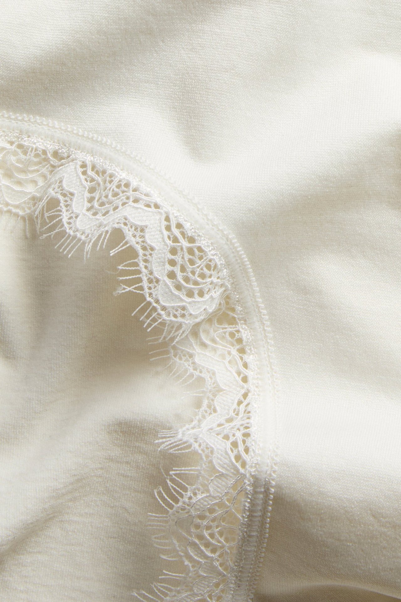 Närbild på offwhite sömlös hög midja hipstertrosa med fin spetskant.