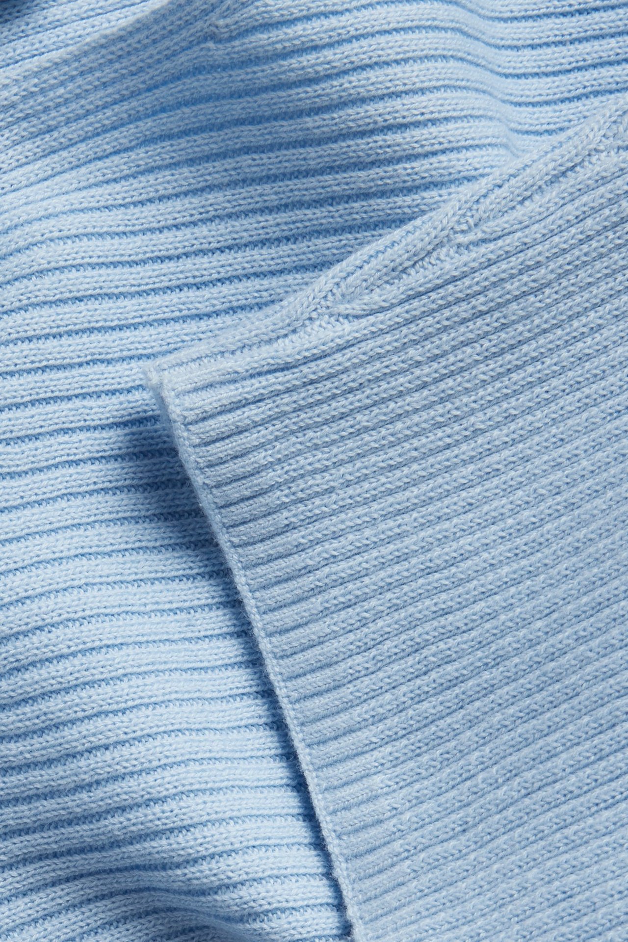 Lähikuva vaaleansinisestä ribbineulepuserosta, joka näyttää kankaan rakenteen.