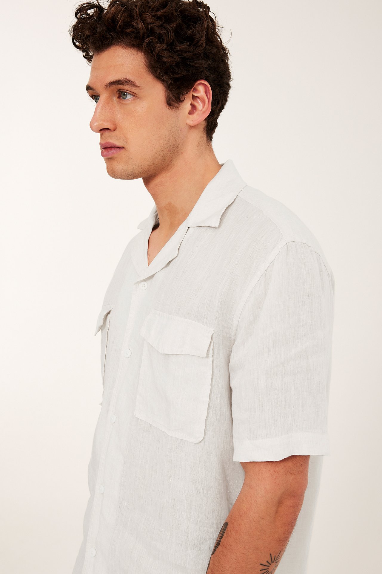 Miehen sivukuva valkoisesta meleeratusta pellavapaidasta, jossa resort-kaulus ja kaksi rintataskua.