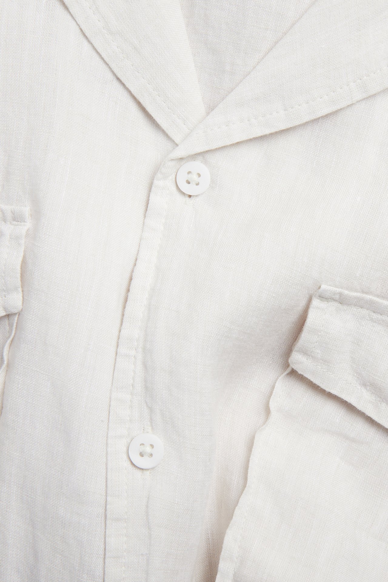 Nærbilde av en hvit melert kortermet linneskjorte med resortkrage, knappelukking og brystlommer.