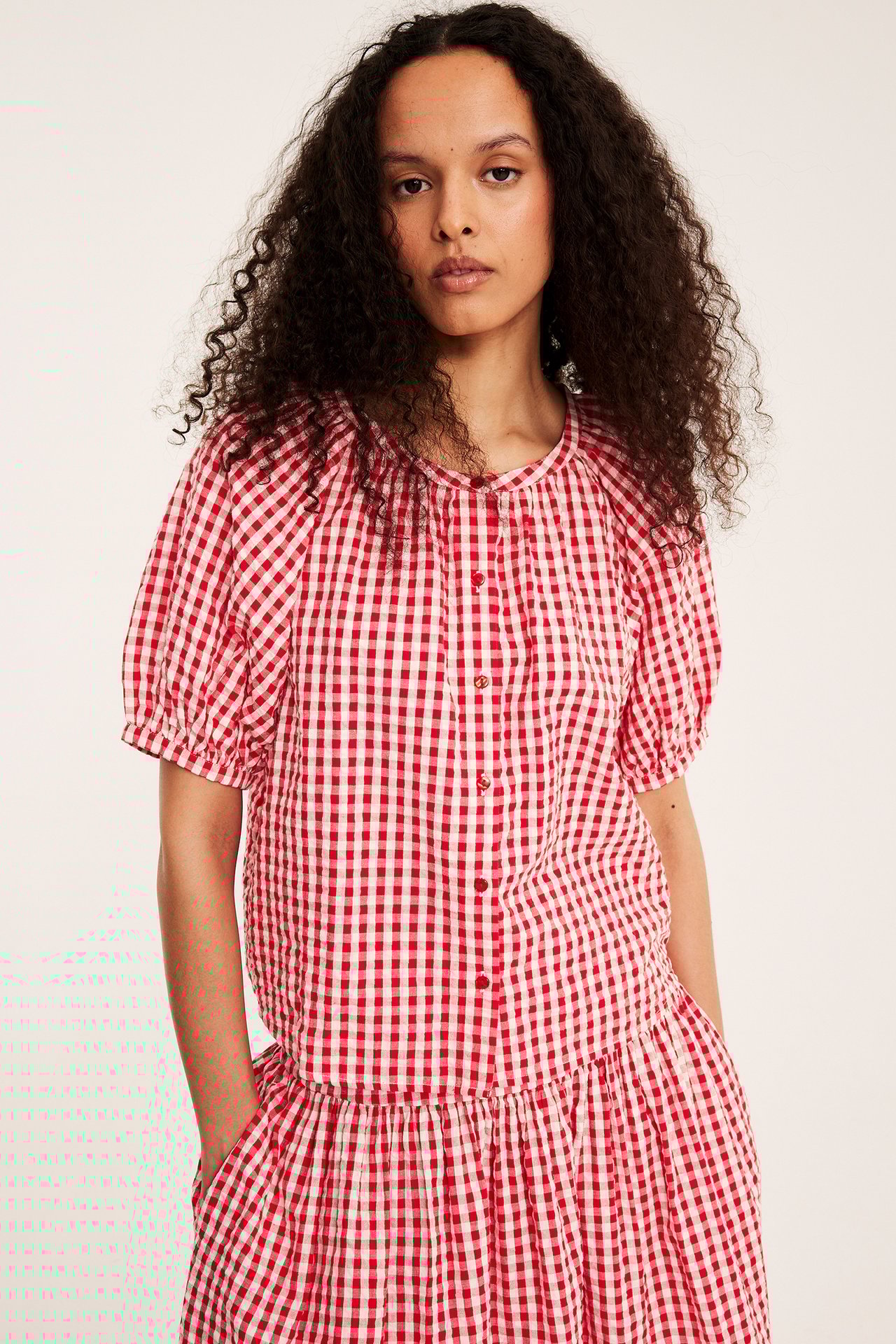 Framsida: Kvinna i rödrutig bäckebölja-blus med puffärm och matchande kjol.