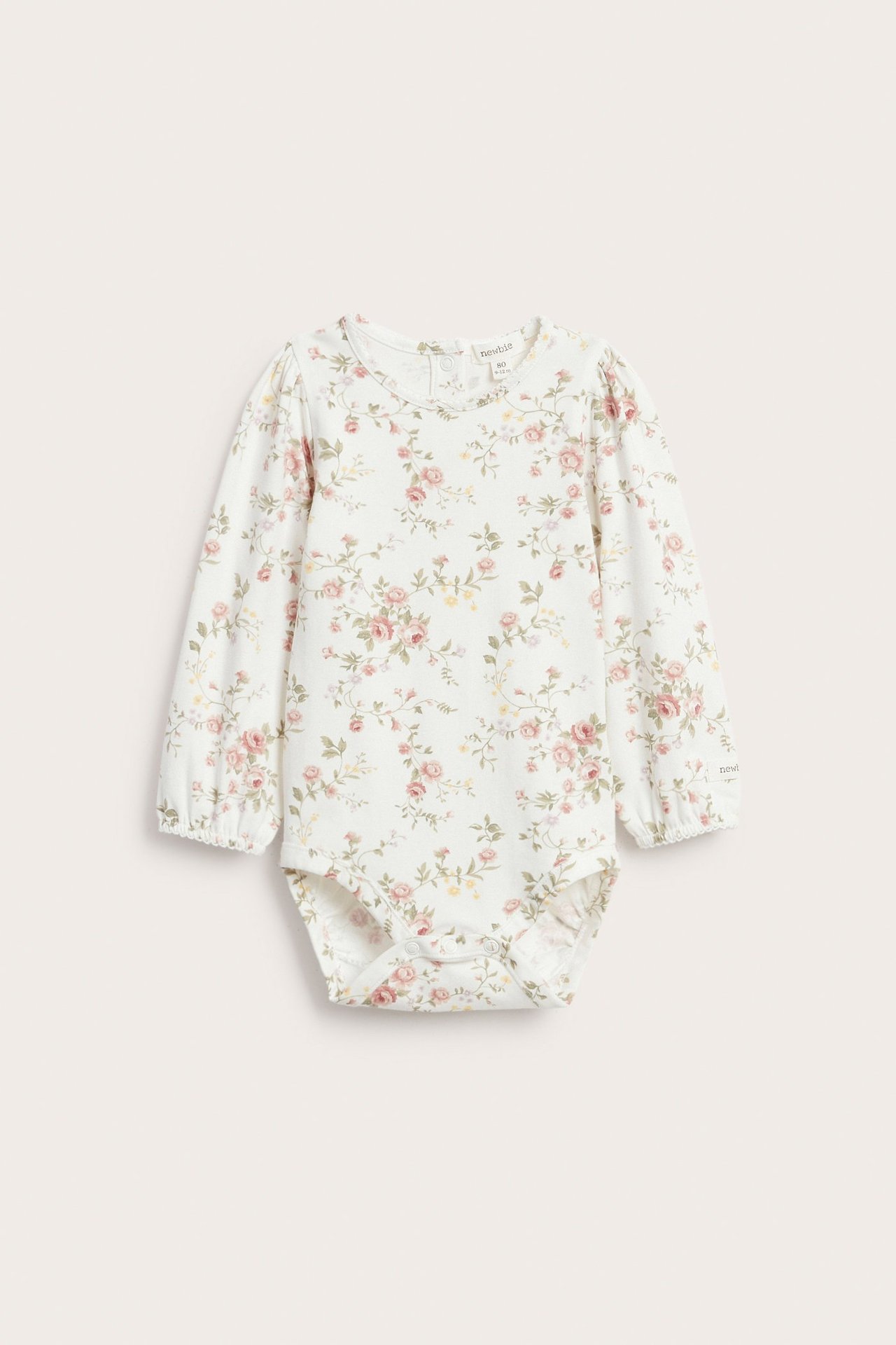 Framifrån, offwhite baby långärmad blommig jerseybody med tryckknappar.