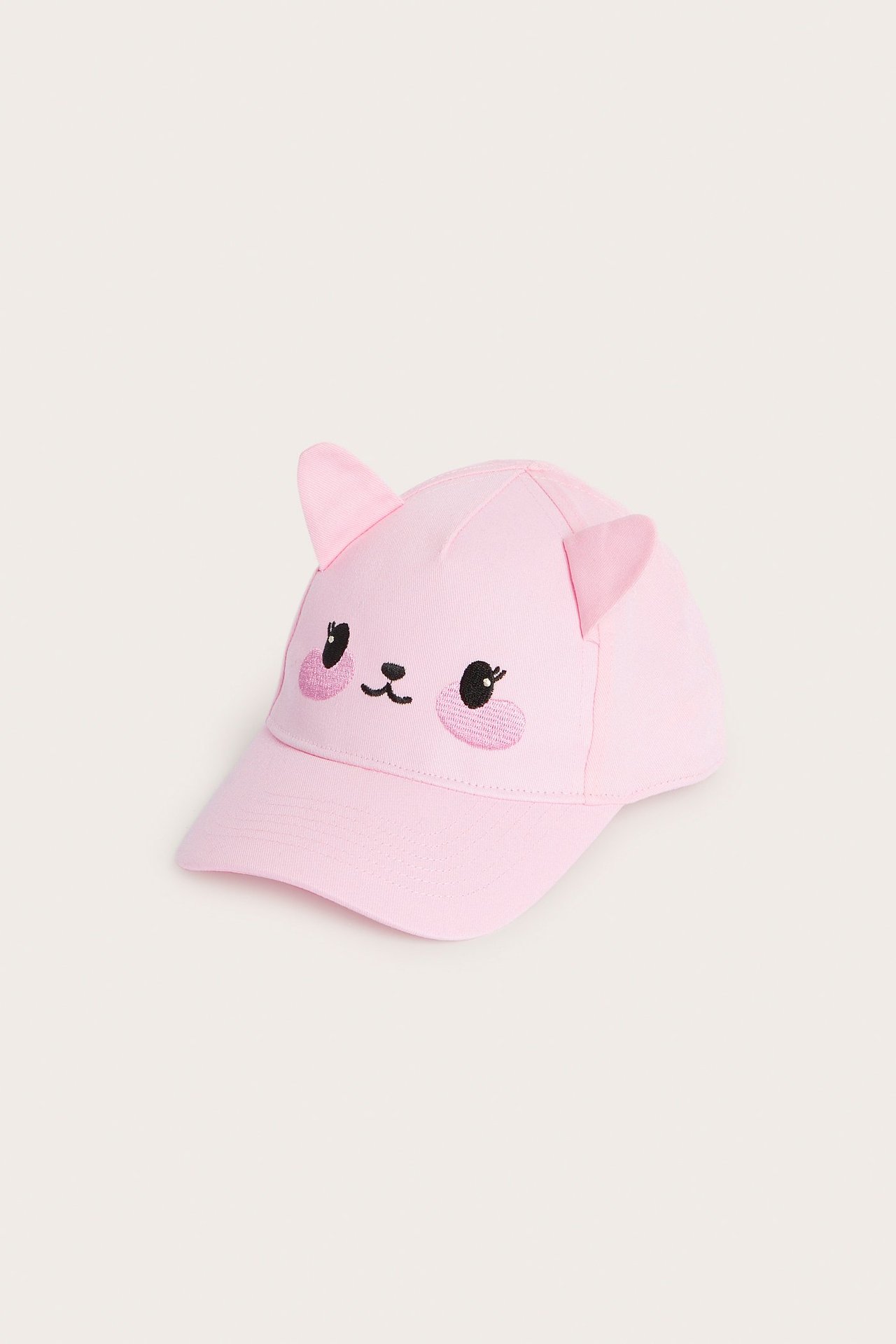 Frontvy av en rosa keps med broderat kattansikte och fastsydda öron.