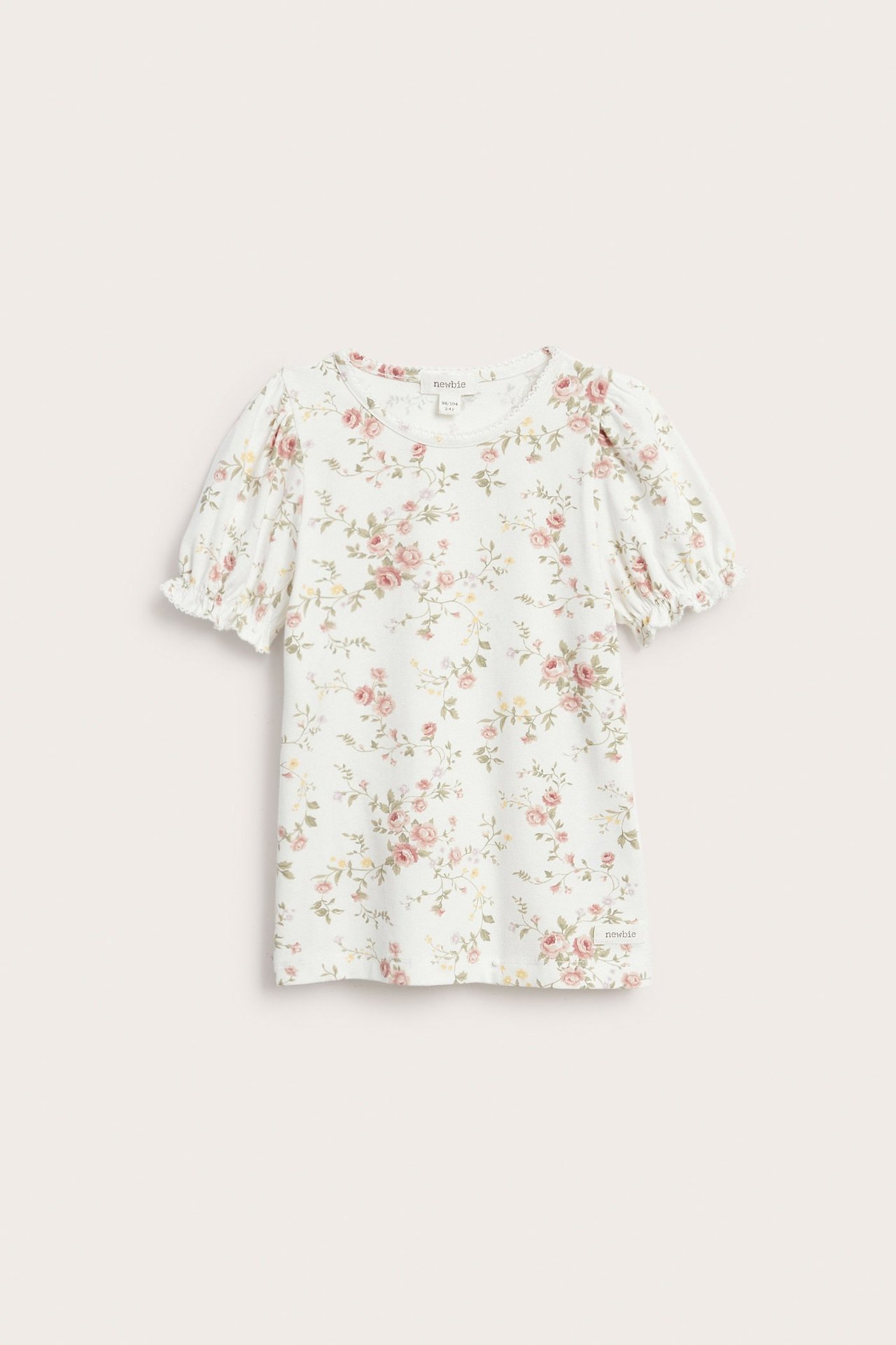 Forfra, offwhite blomstret jerseytopp for barn med korte puffermer og elastiske mansjetter.