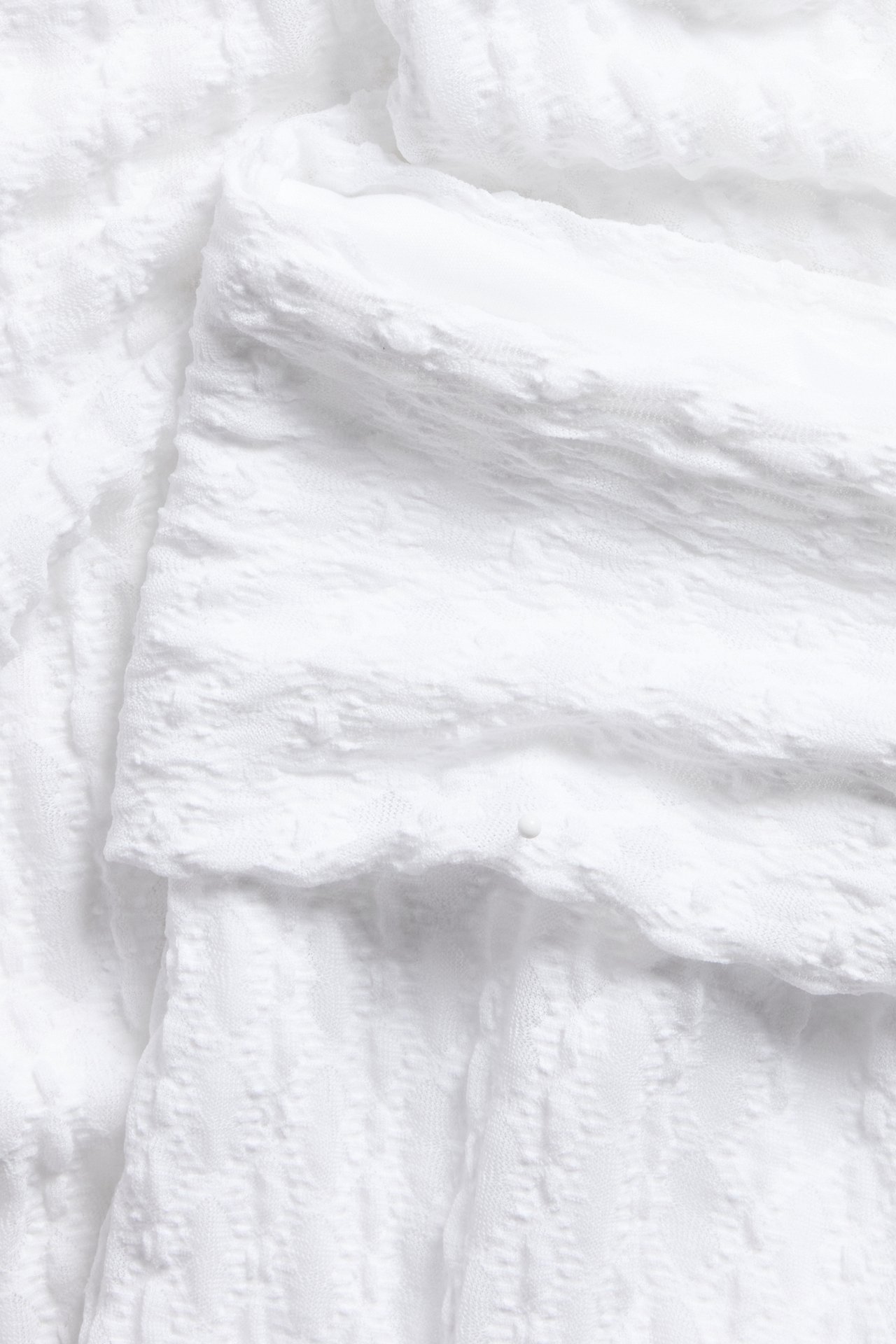 Lähikuva valkoisista joogahousuista, joissa on taitettava vyötärö ja hienovarainen pitsikuvio.