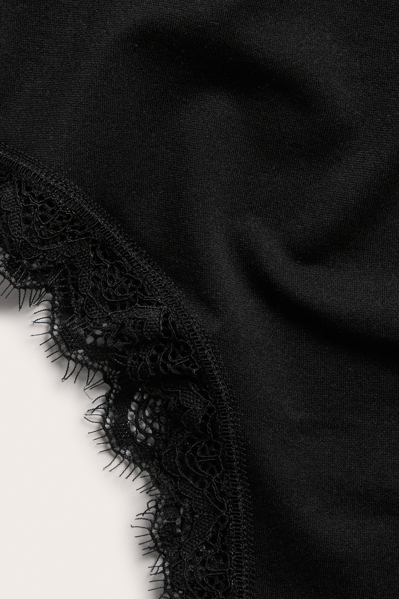 Närbild av enfärgade svarta cheeky trosor med en delikat svart spetskant.