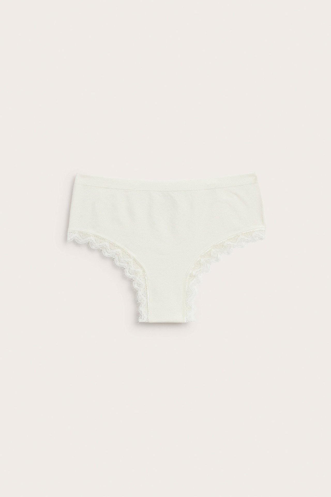 Frontbilde av offwhite cheeky-truser med hvit blondekant langs benåpningene.