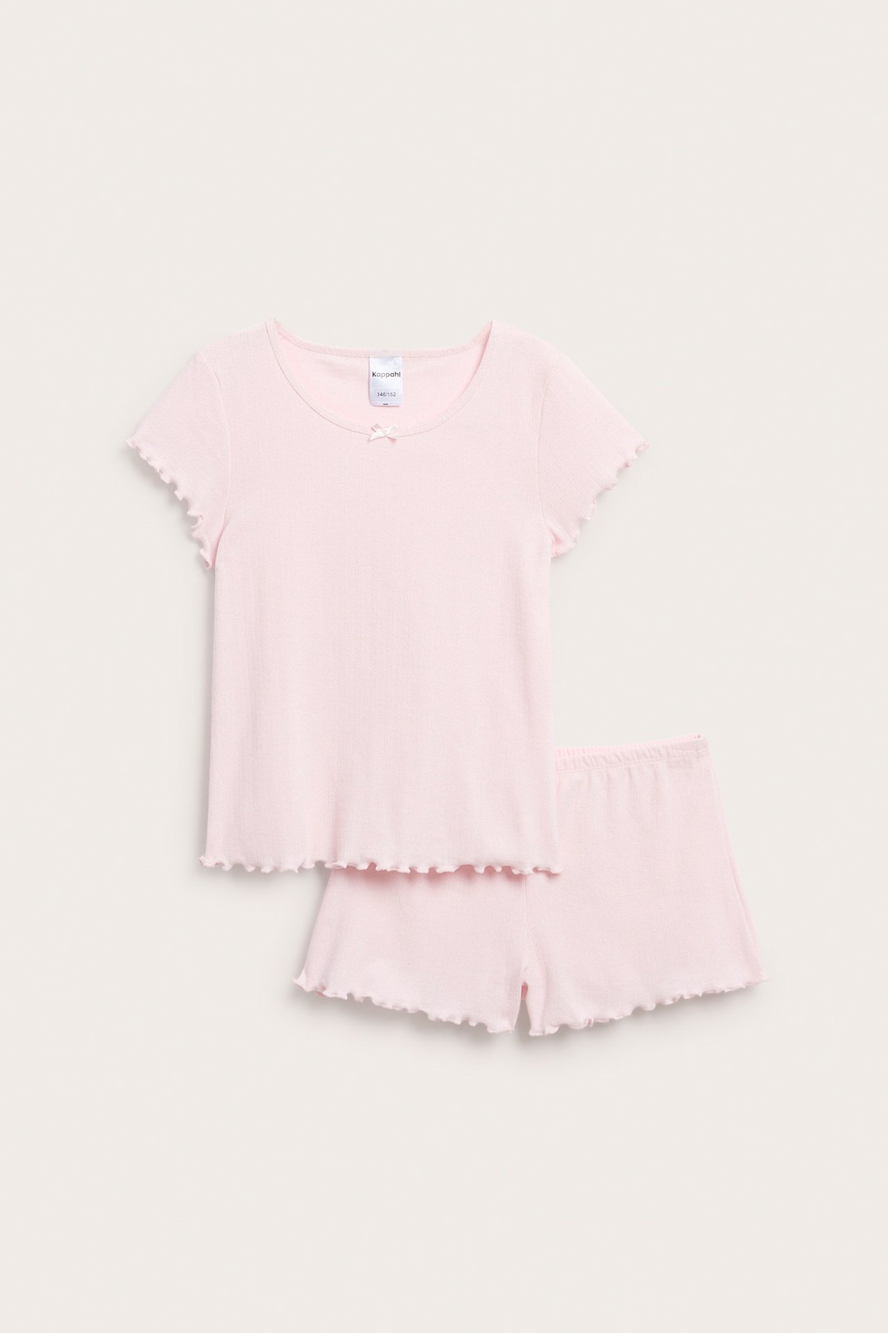 Framsida av ljusrosa pointelle pyjamasset för barn: kortärmad topp och matchande volangshorts.