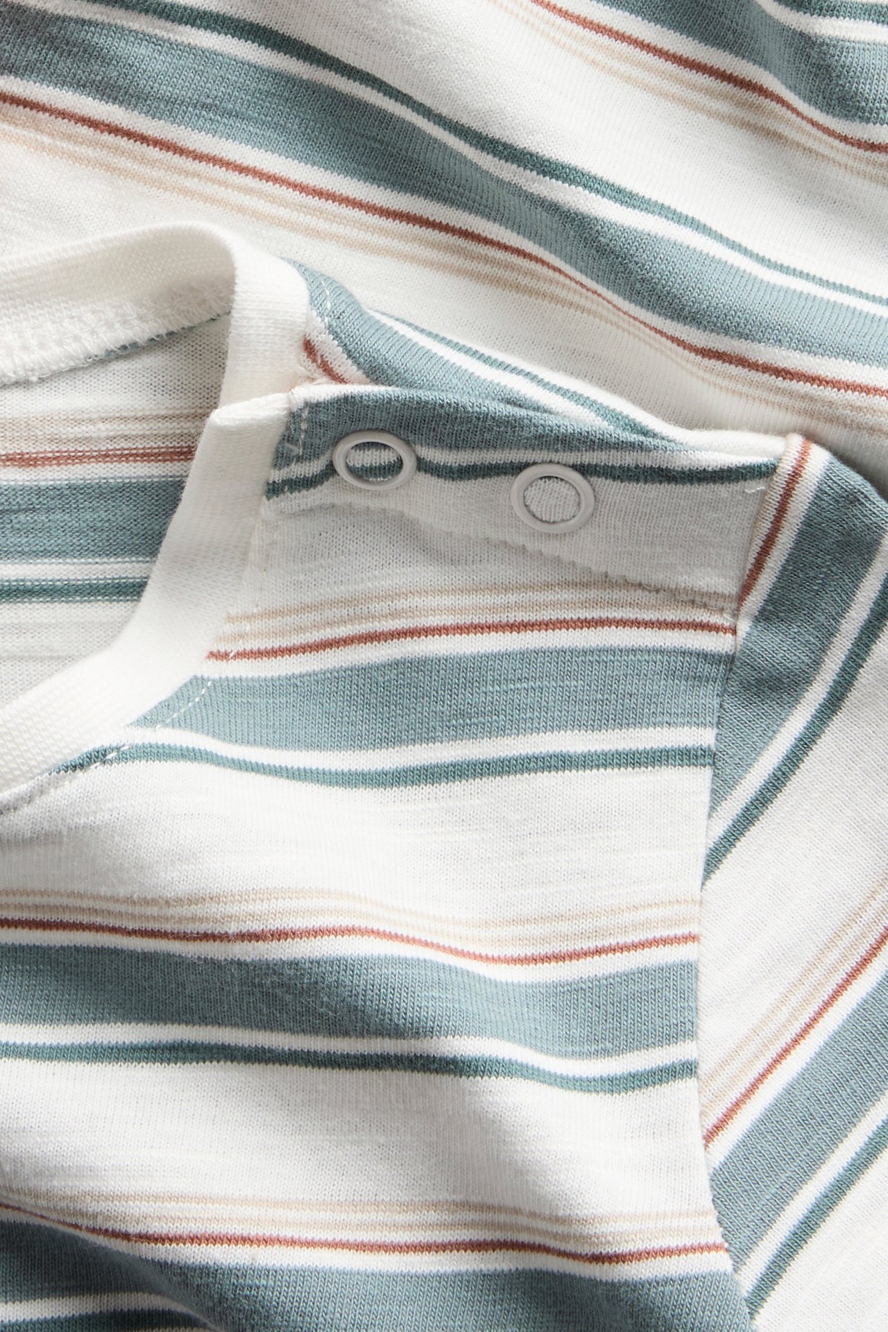 Lähikuva offwhite-raidallisesta lyhythihaisesta vauvanbodysta, jossa turkooseja ja ruskeita raitoja, olalla nepparit.