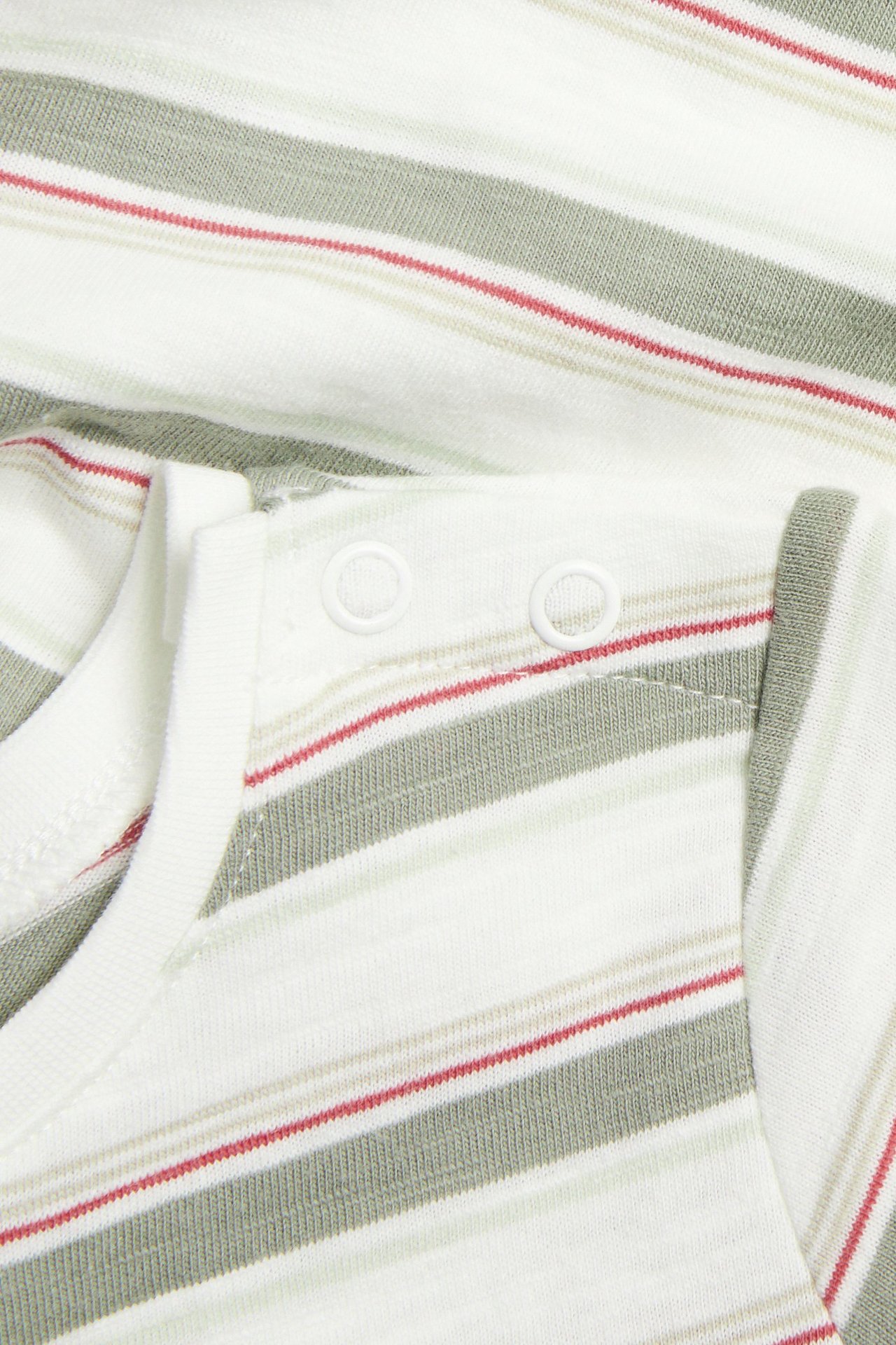 Närbild på en offwhite-randig babybody med gröna och röda ränder samt vita tryckknappar på axeln.
