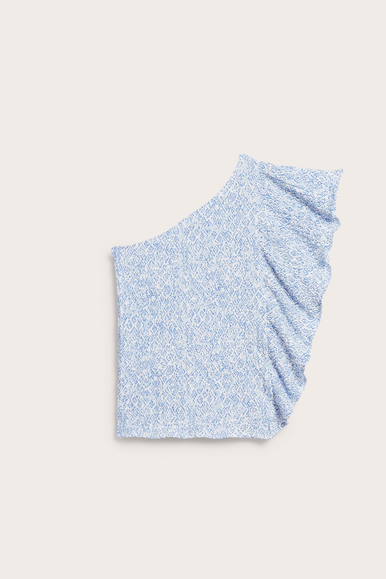 Edestäpäin kuvattu lasten vaaleansininen kuviollinen one shoulder -toppi, jossa on röyhelö sivulla.