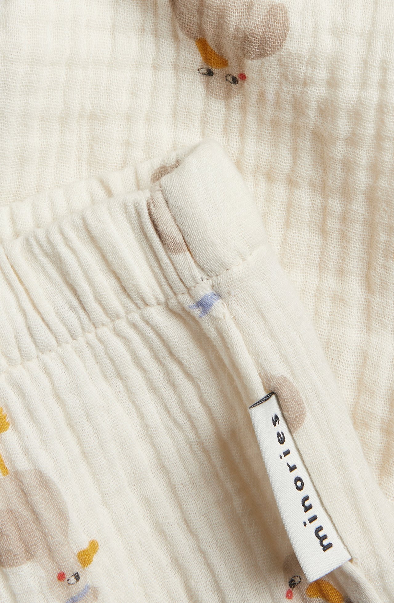 Lähikuva beigevärisistä kuvioiduista musliinivauvanhousuista, joissa on joustava vyötärö.