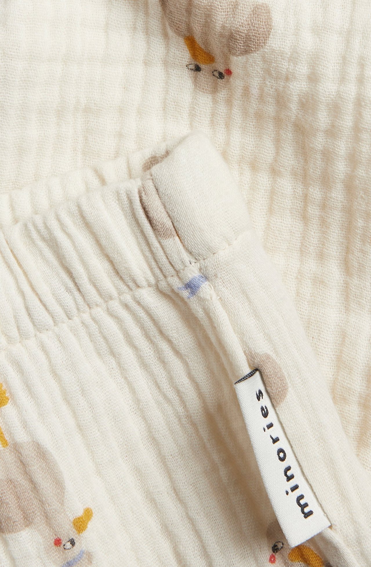 Närbild av beiga mönstrade babybyxor i muslin med resår i midjan.