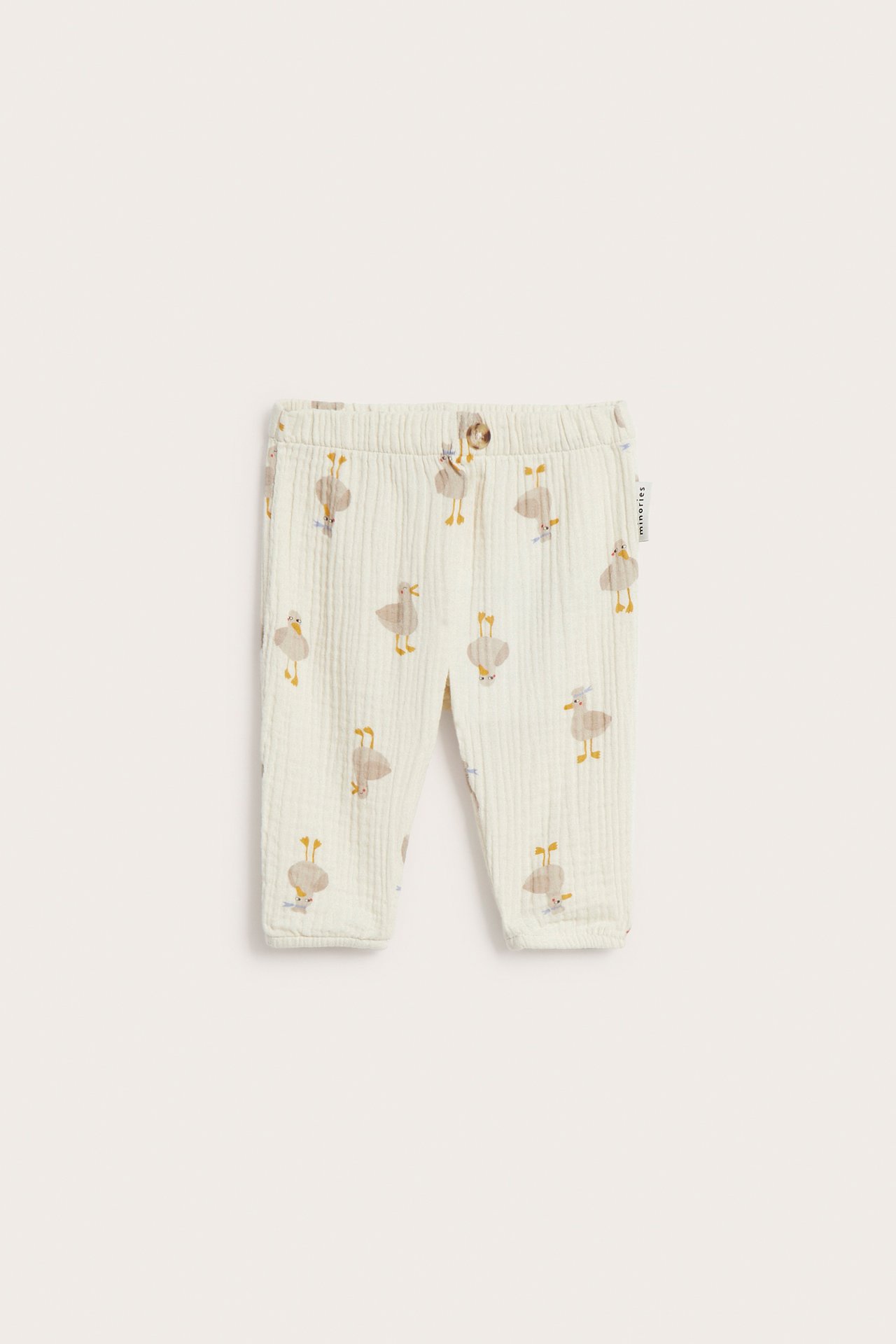 Edestä, vaaleanbeiget vauvan musliinihousut joustovyötäröllä, valenapilla ja lintukuviolla.