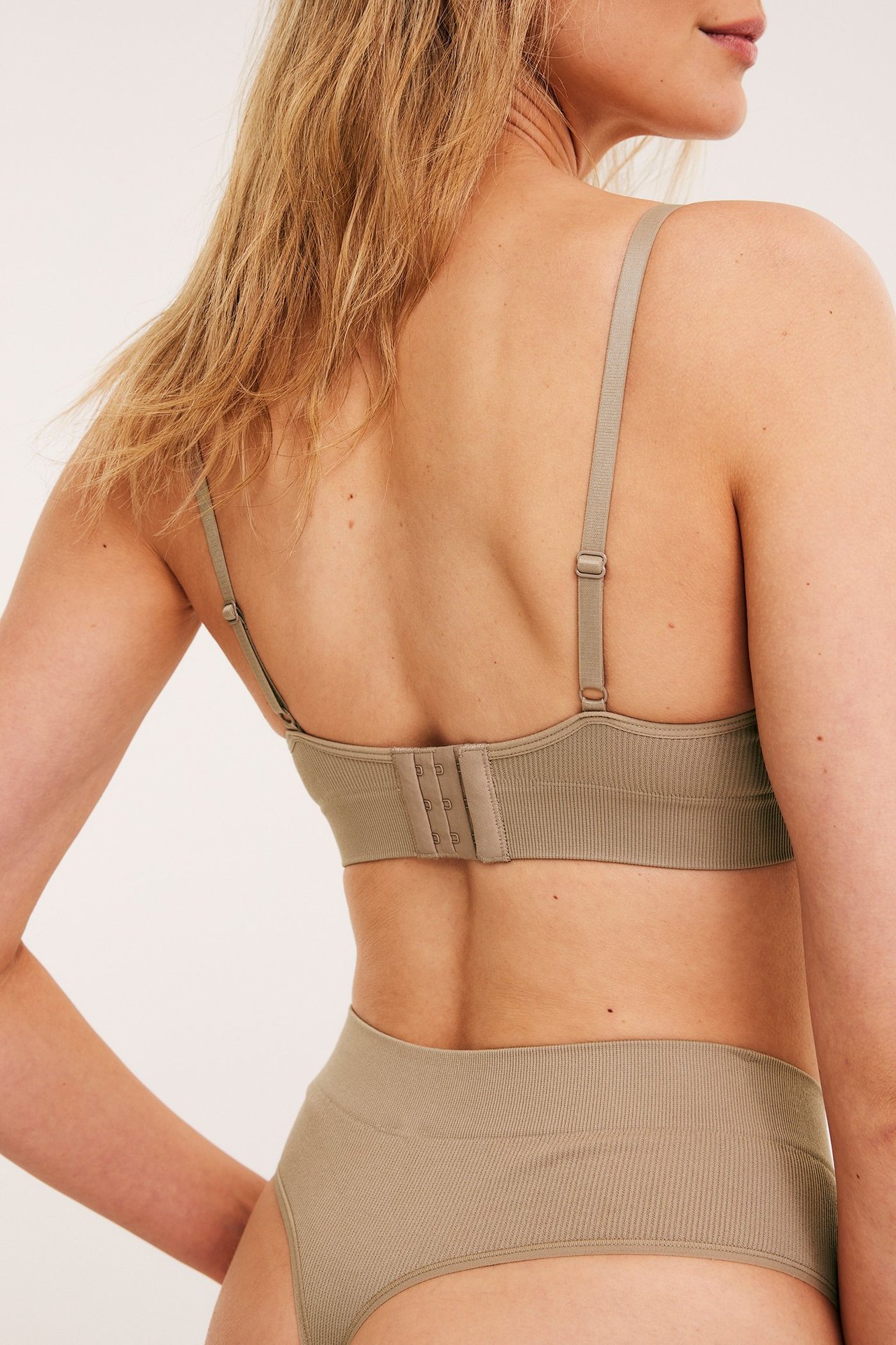 Widok od tyłu: kobieta w brązowym prążkowanym bezszwowym biustonoszu soft z zapięciem i majtkami.