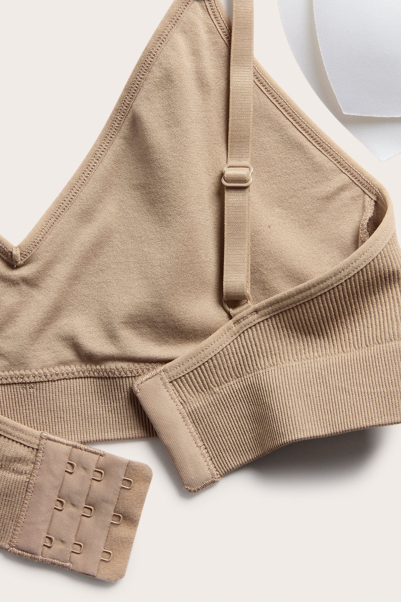 Närbild: Brun sömlös ribbad mjuk-bh med justerbara band, hakknäppning och vit vaddering.