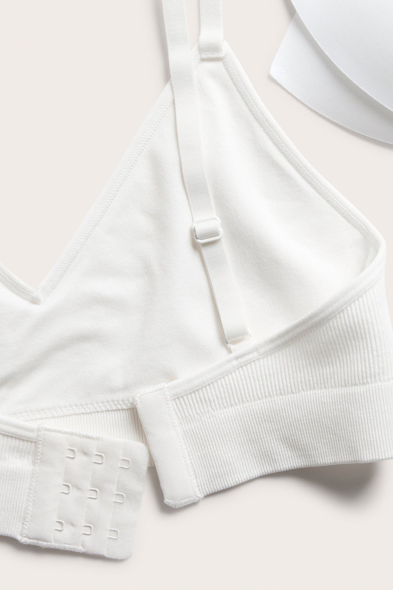 Närbild av en vit ribbad seamless soft-bh med justerbara band, hyskknäppning och uttagbar vaddering.