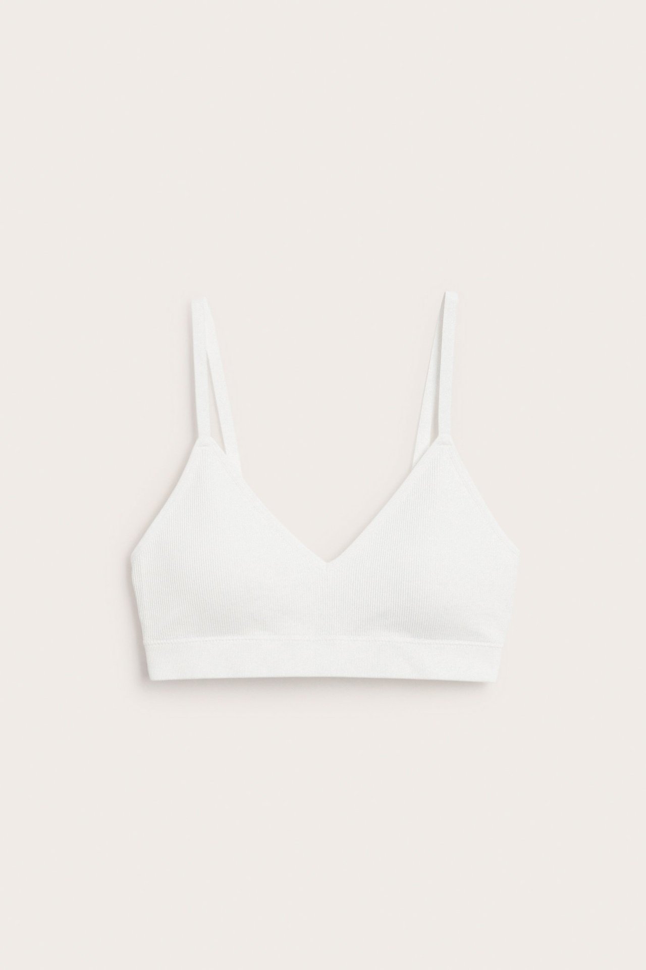 Frontvisning av en hvit sømløs ribbet soft-BH med V-hals og justerbare stropper.