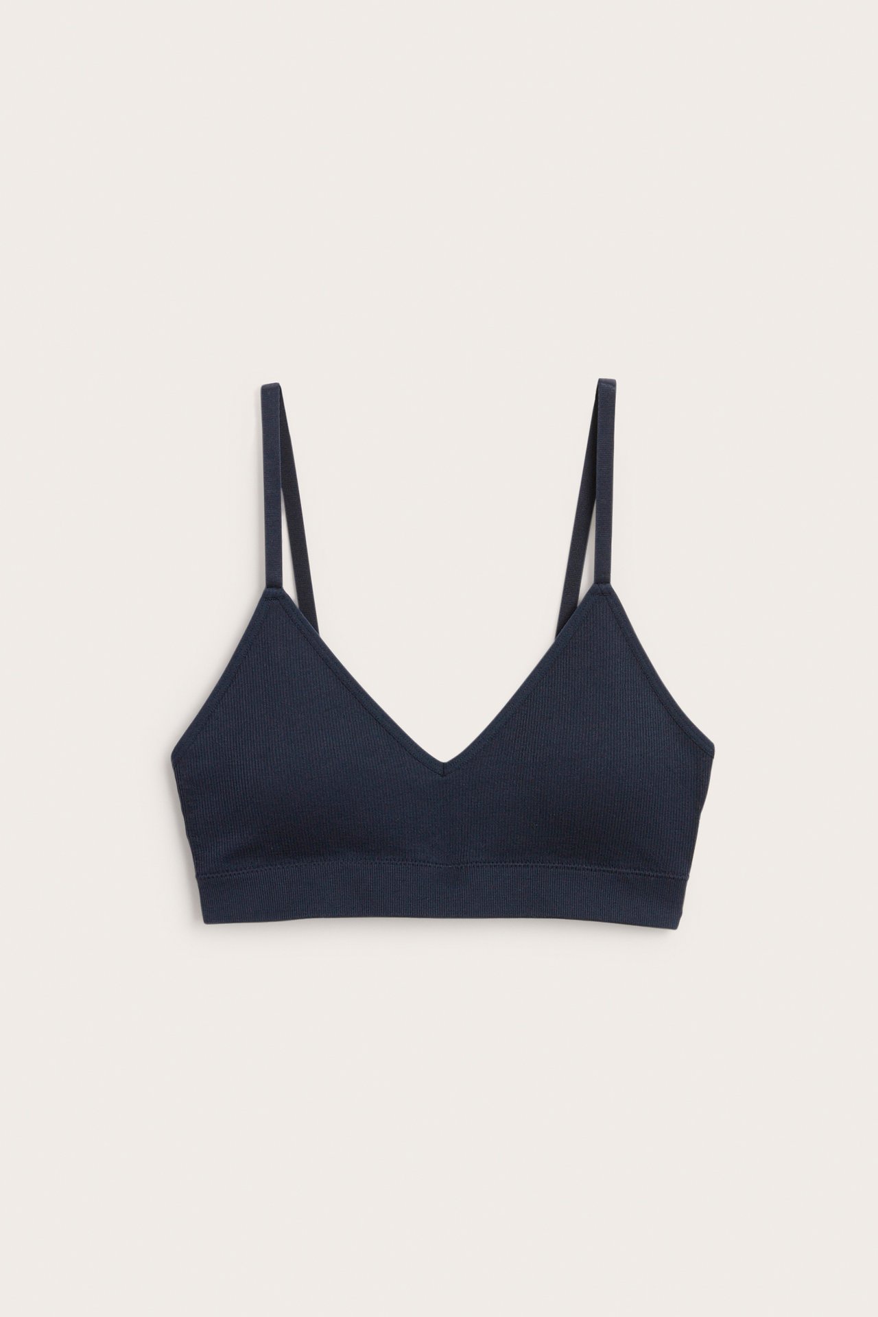 Framifrån, mörkblå ribbad sömlös mjuk-bh med justerbara axelband och V-ringning.