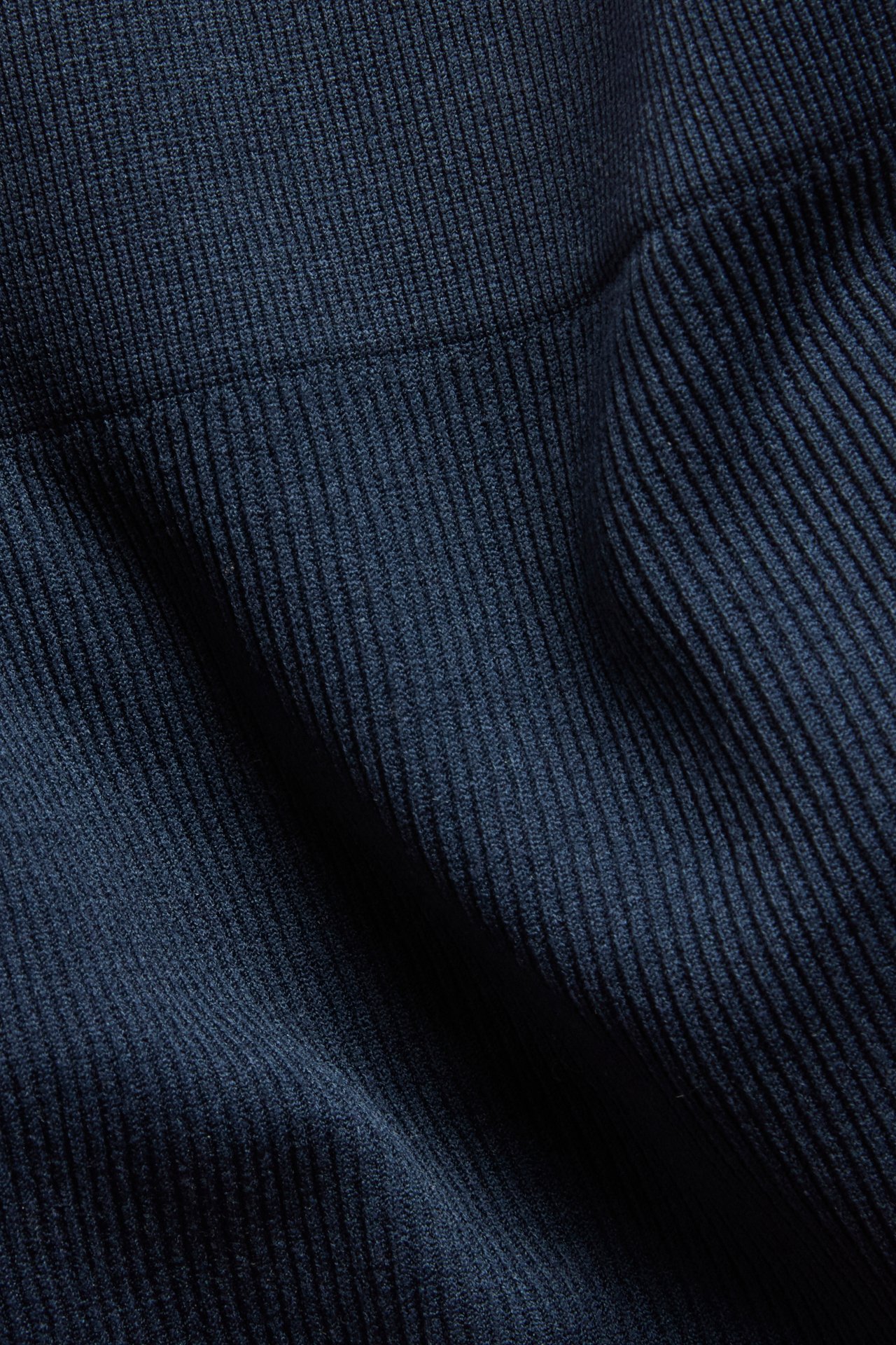 Närbild av mörkblått ribbat tyg på en sömlös stringtrosa med strukturerat mönster.