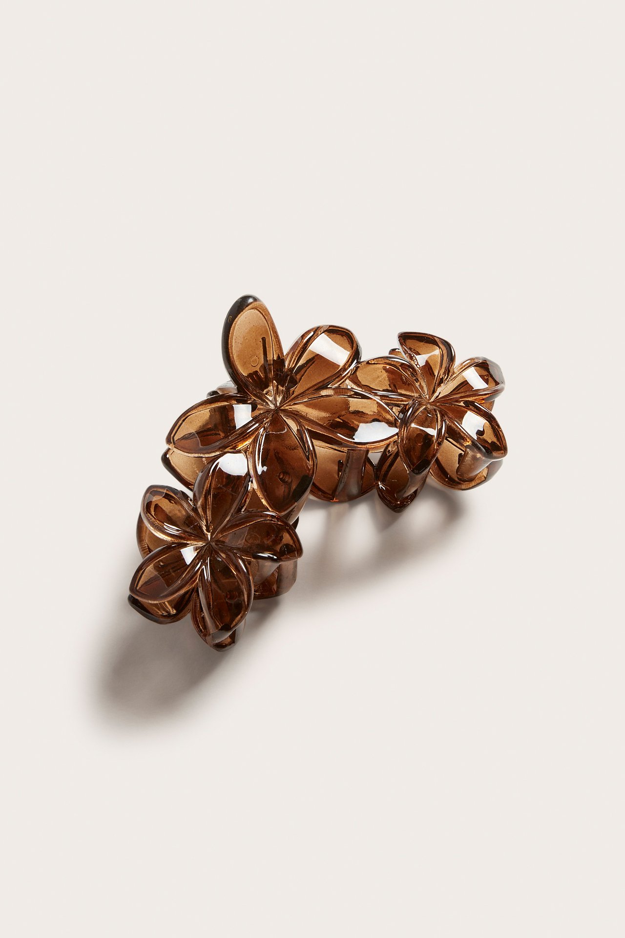 Lähikuva, ylhäältä, läpikuultavasta ruskeasta hiusklipsistä, jossa on useita kukkamuotoisia yksityiskohtia.