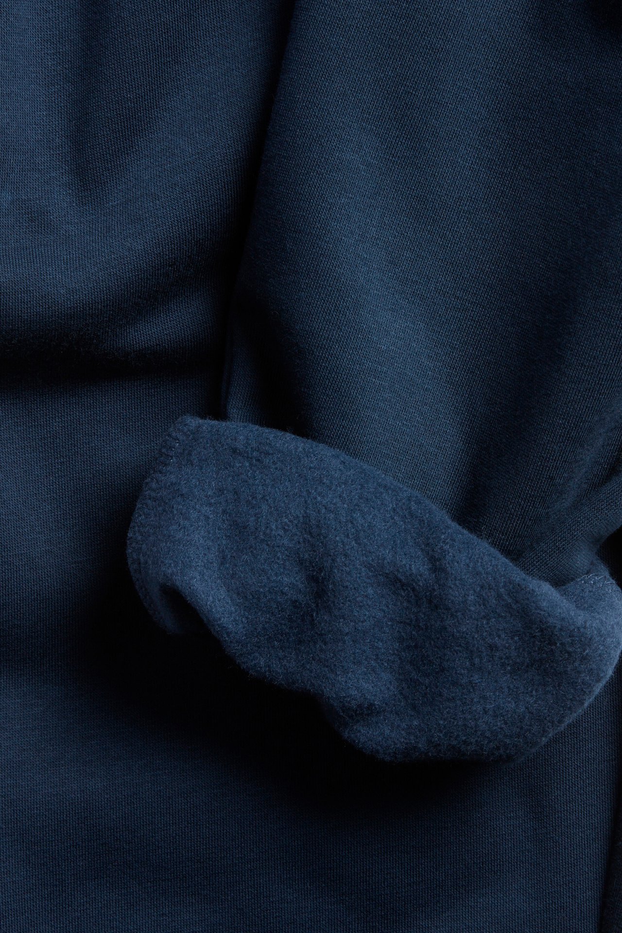 Zbliżenie na granatowe spodnie dresowe, pokazujące szczotkowaną stronę wewnętrzną miękkiej bawełny.