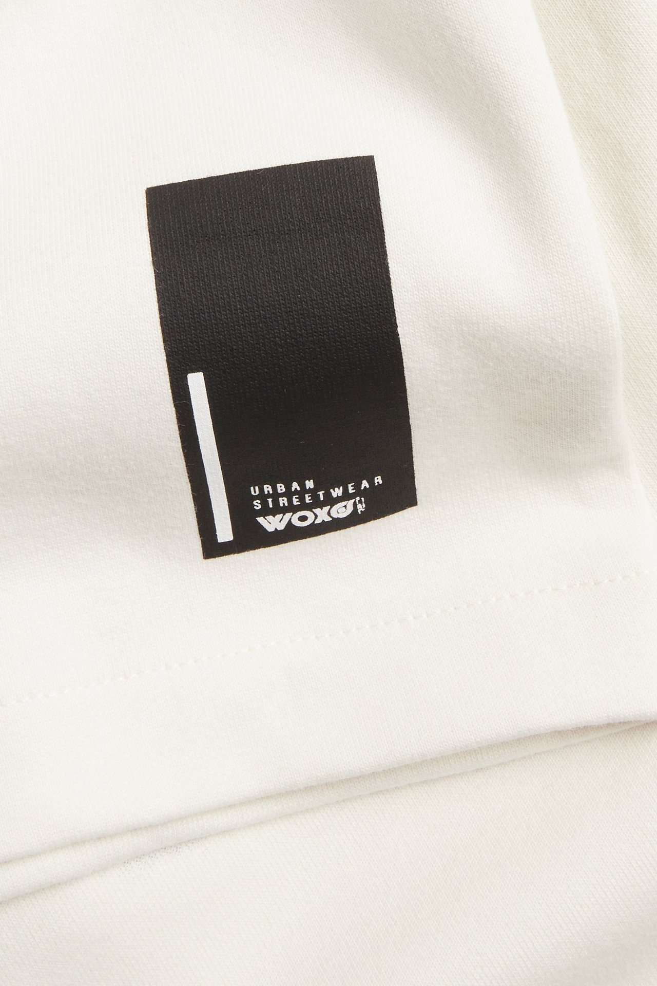 Lähikuva valkoisesta oversized-t-paidasta, jossa on suuri mustavalkoinen etutekstipainatus.