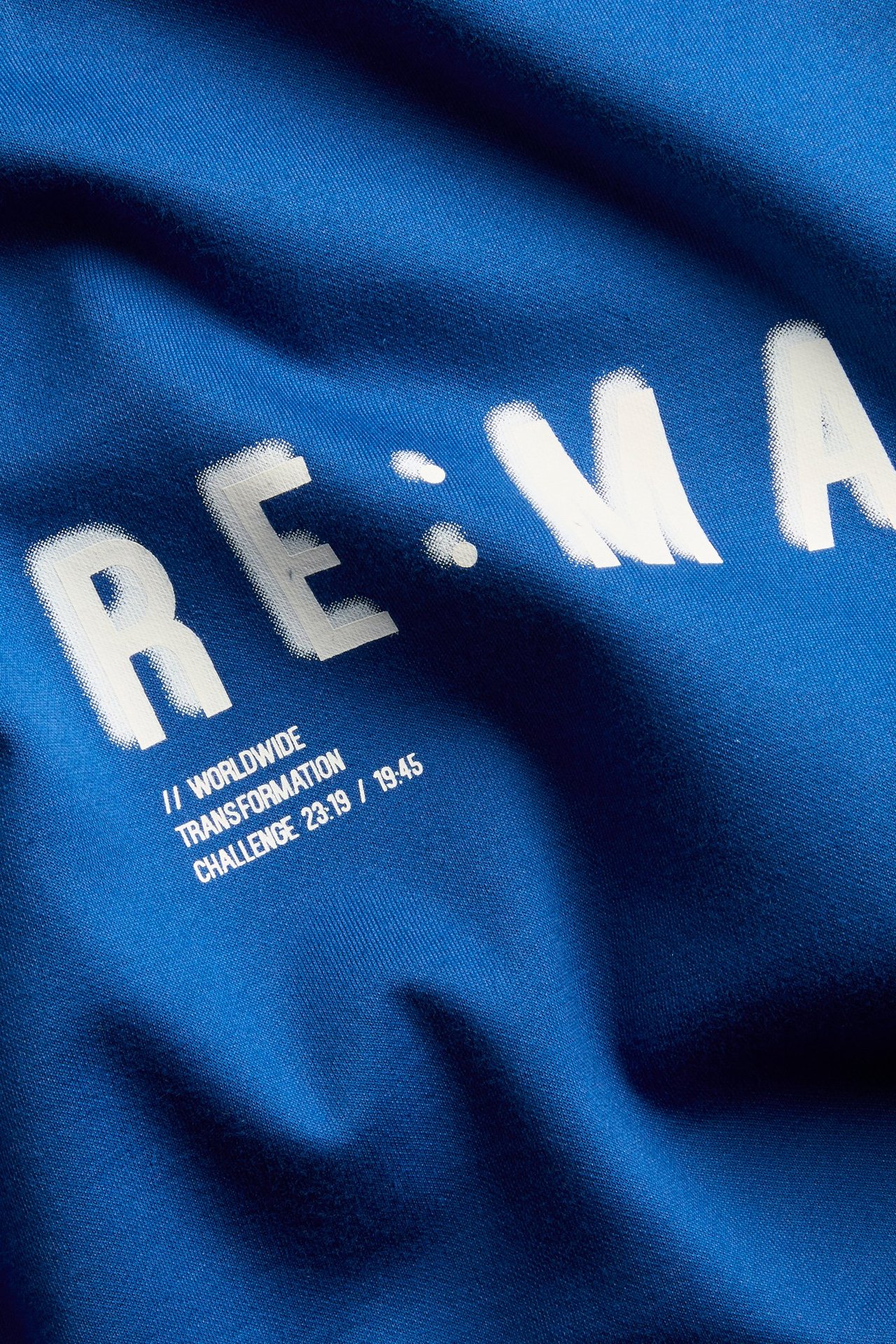 Närbild på en mörkblå oversized t-shirt med vitt texttryck framtill.