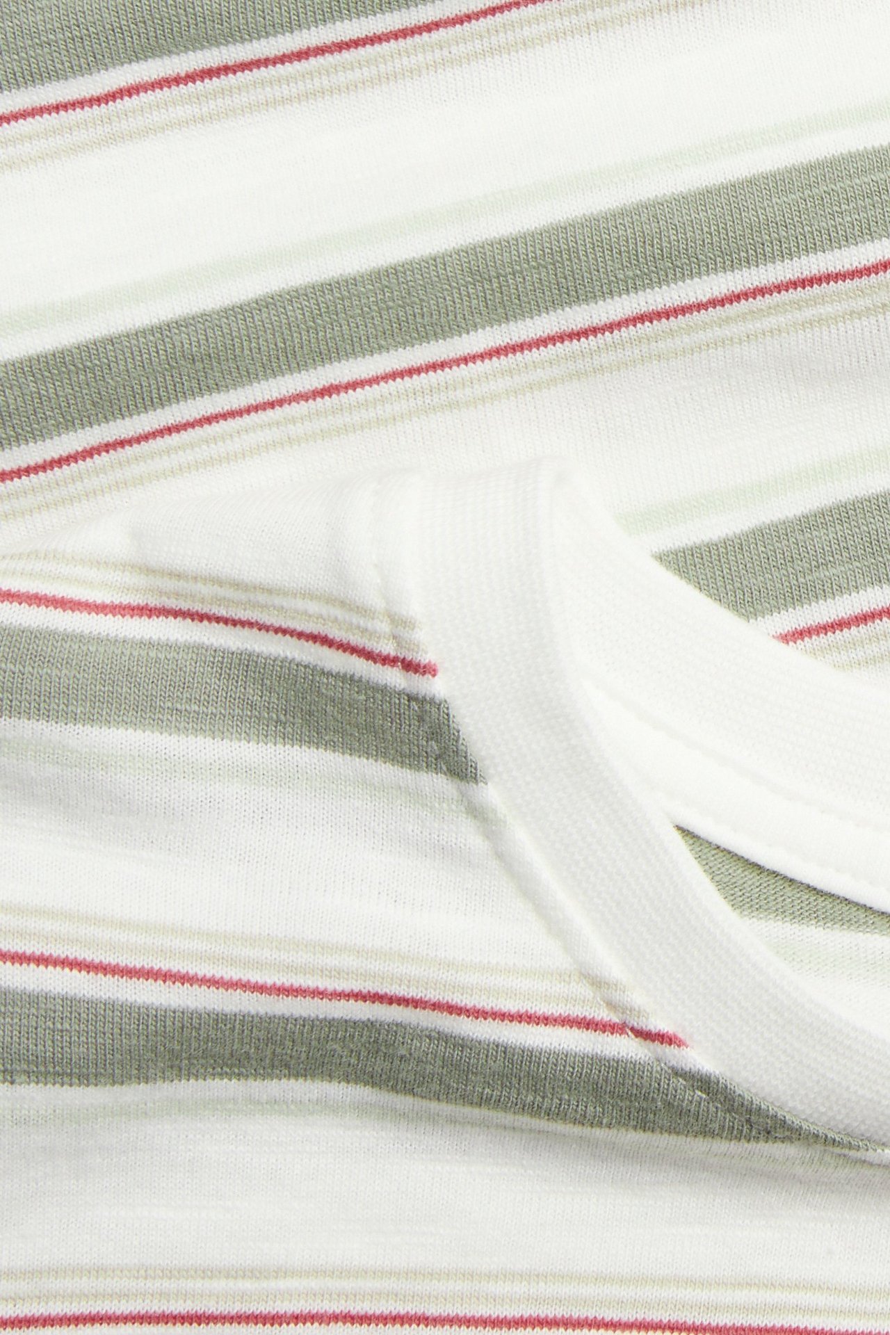 Närbild av offwhite randig bomullsslub t-shirt med grågröna, beiga, röda ränder och uppvikt mudd.