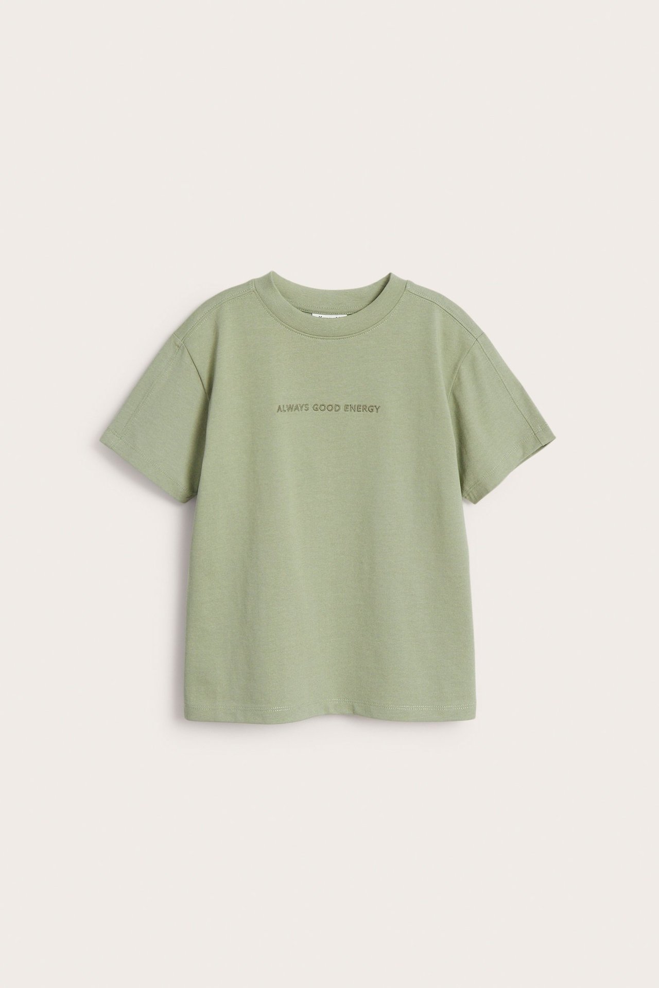 Framsida av en barns oversized salviagrön bomulls-t-shirt med 'ALWAYS GOOD ENERGY' broderat framtill.