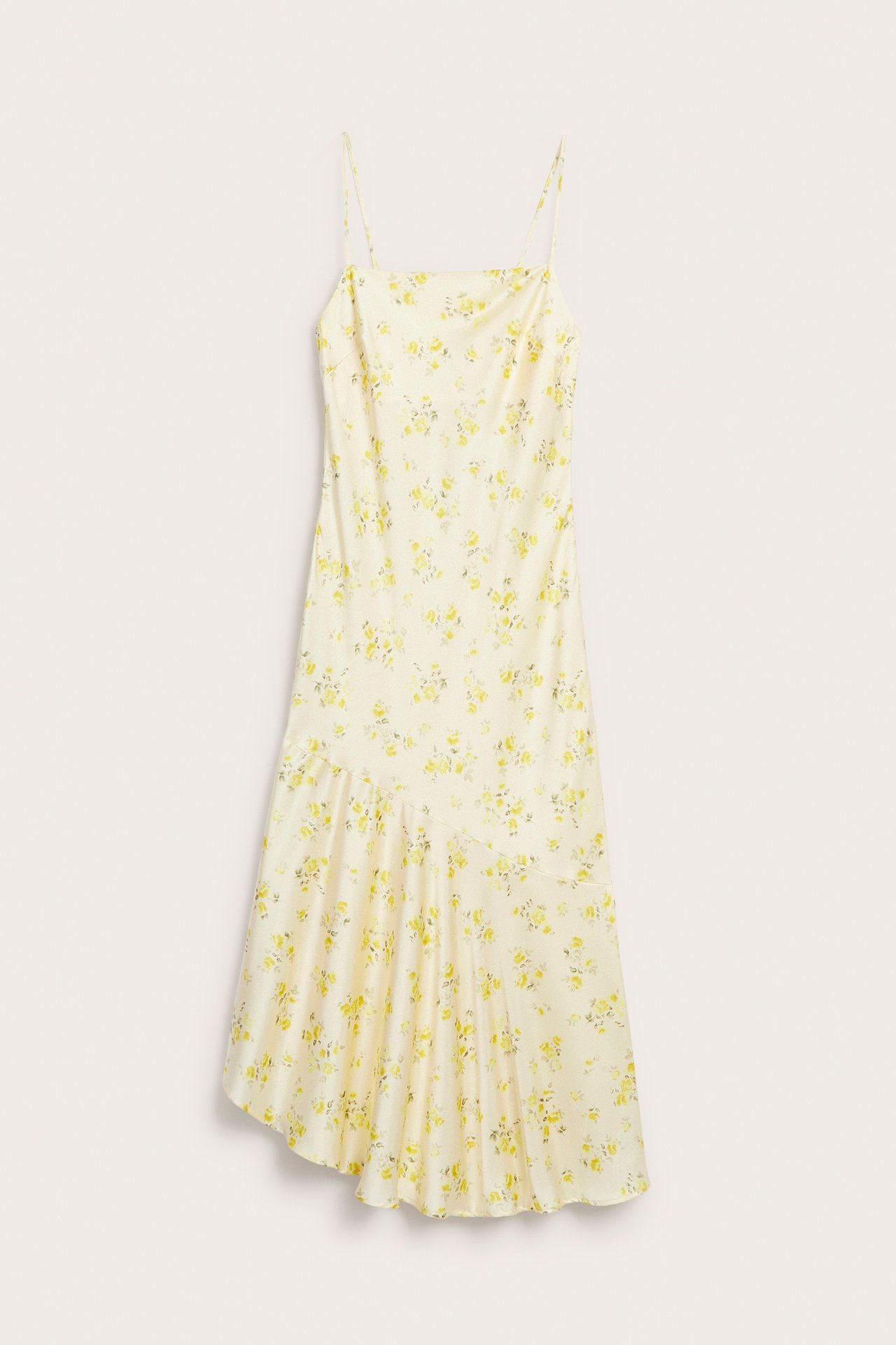 Frontvisning av en lys gul jacquard slipkjole med tynne stropper, blomstermønster og asymmetrisk kant.