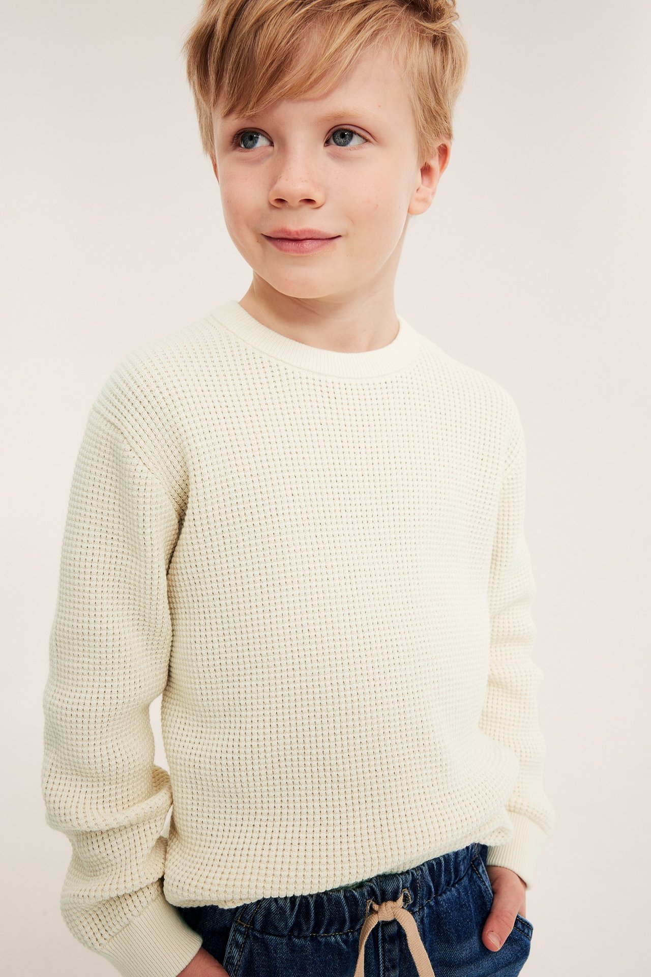 Barn i lys beige bomullsgenser med ribb i nederkant, hals og ermene.