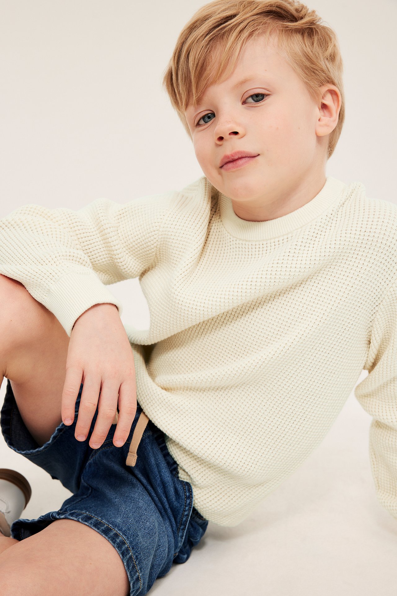 Lys beige bomullstrøye med ribber, gutt sitter i jeans.