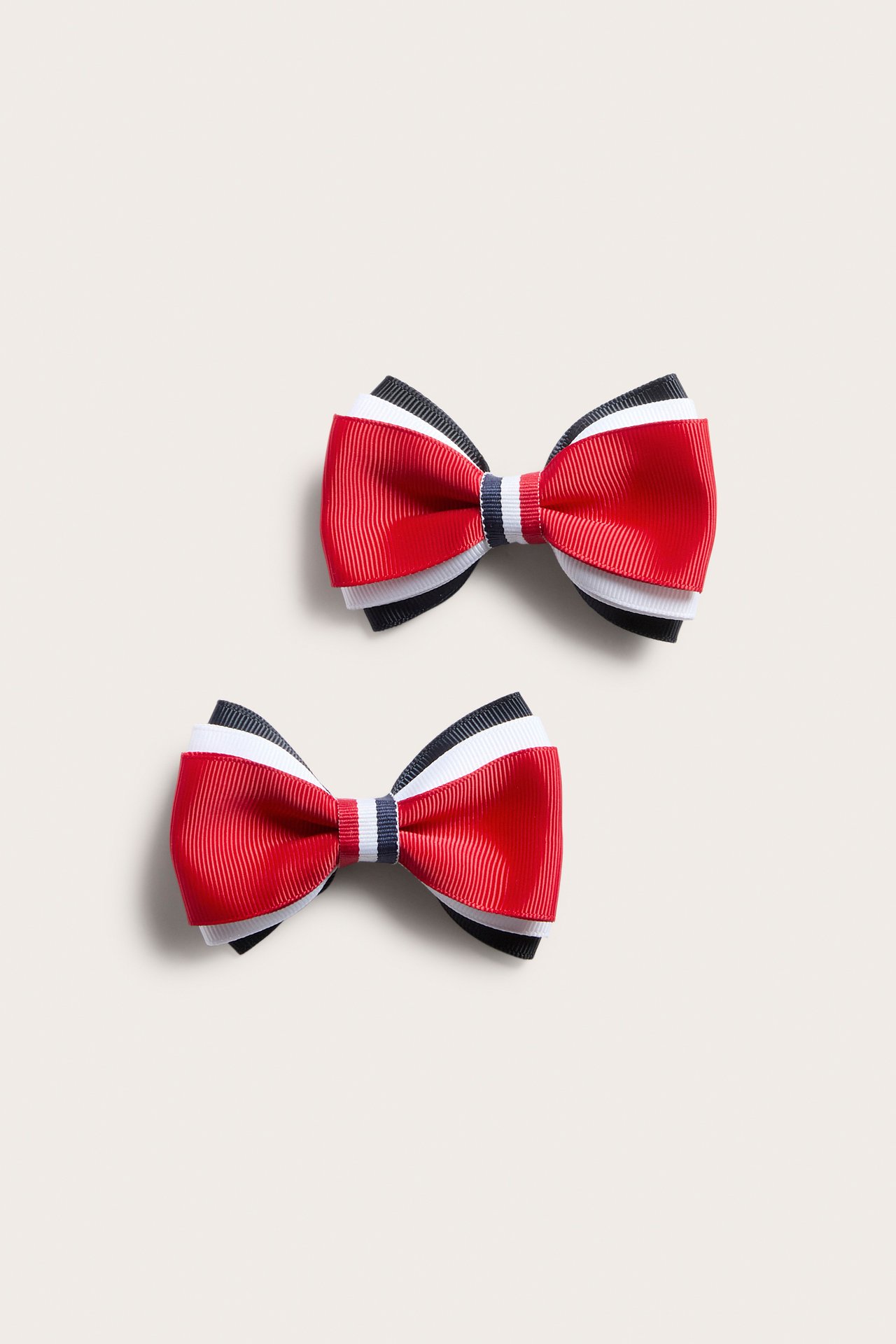 Widok z góry na 2-pak czerwono-biało-granatowych teksturowanych kokardek do włosów.