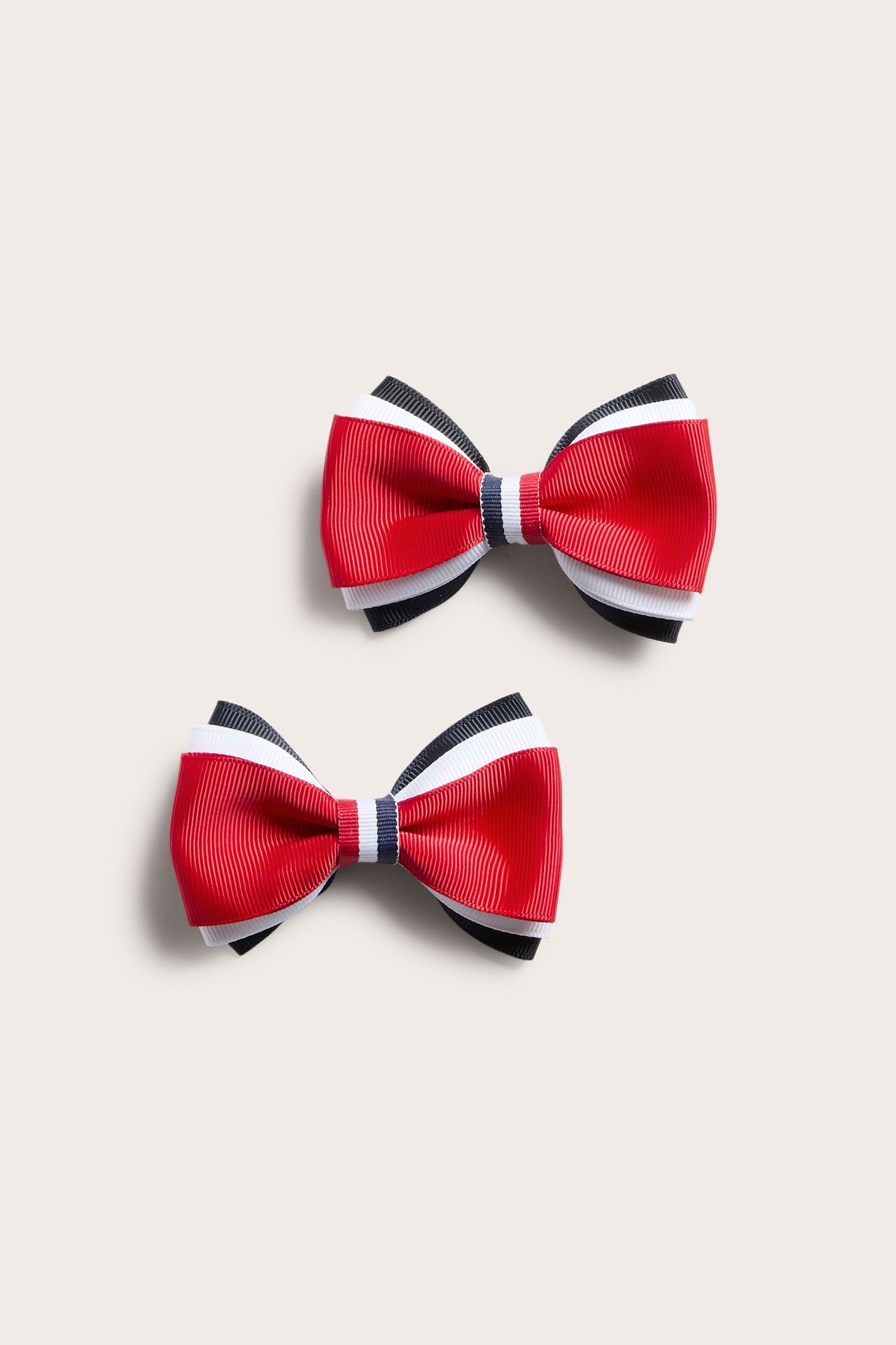 Widok z góry na 2-pak czerwono-biało-granatowych teksturowanych kokardek do włosów.