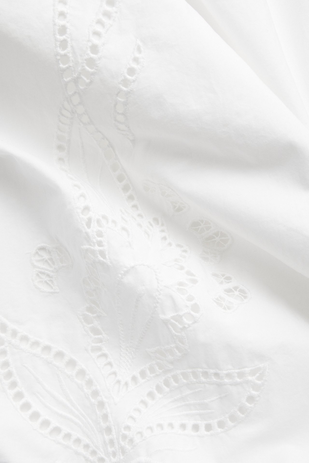 Lähikuva valkoisesta, väljästä puuvillapopliinihameesta yksityiskohtaisella valkoisella kirjailulla.