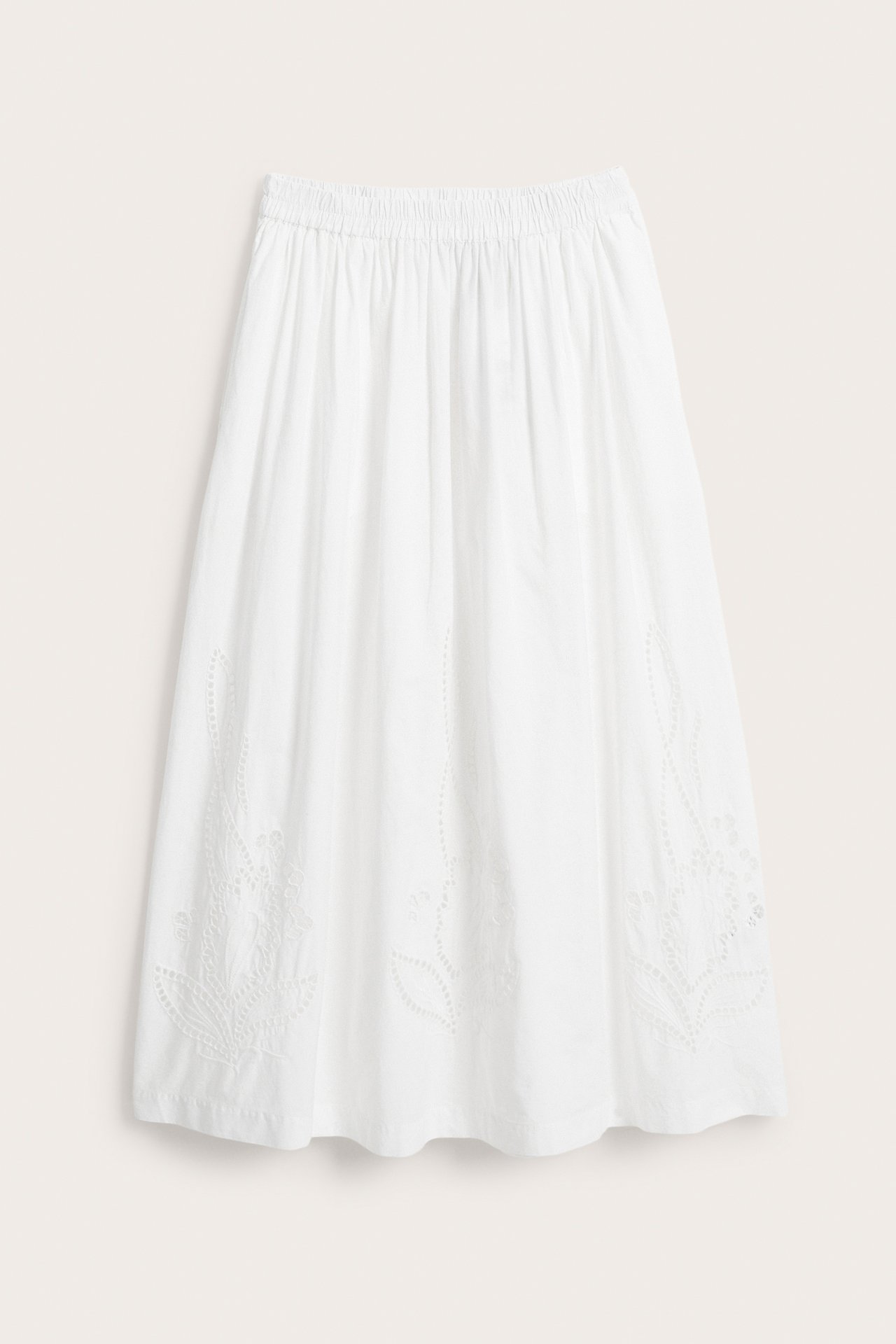 Valkoinen leveä puuvillapopliinihame, resori vyötäröllä ja herkkä kirjailu helmassa, edestäpäin.