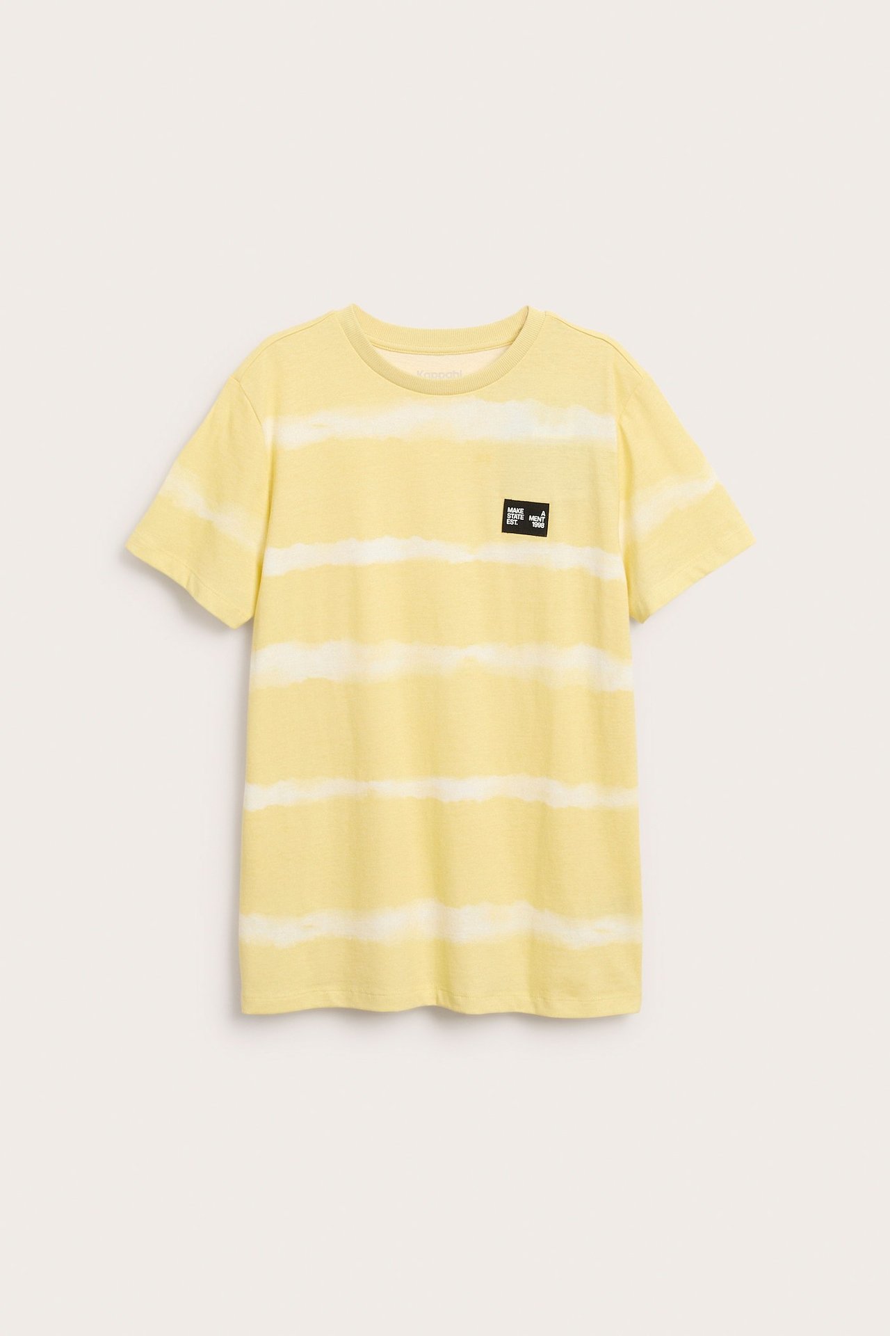 Framifrån: Kortärmad t-shirt för barn i gul och off-white batikmönstrad bomull med bröstmärke.